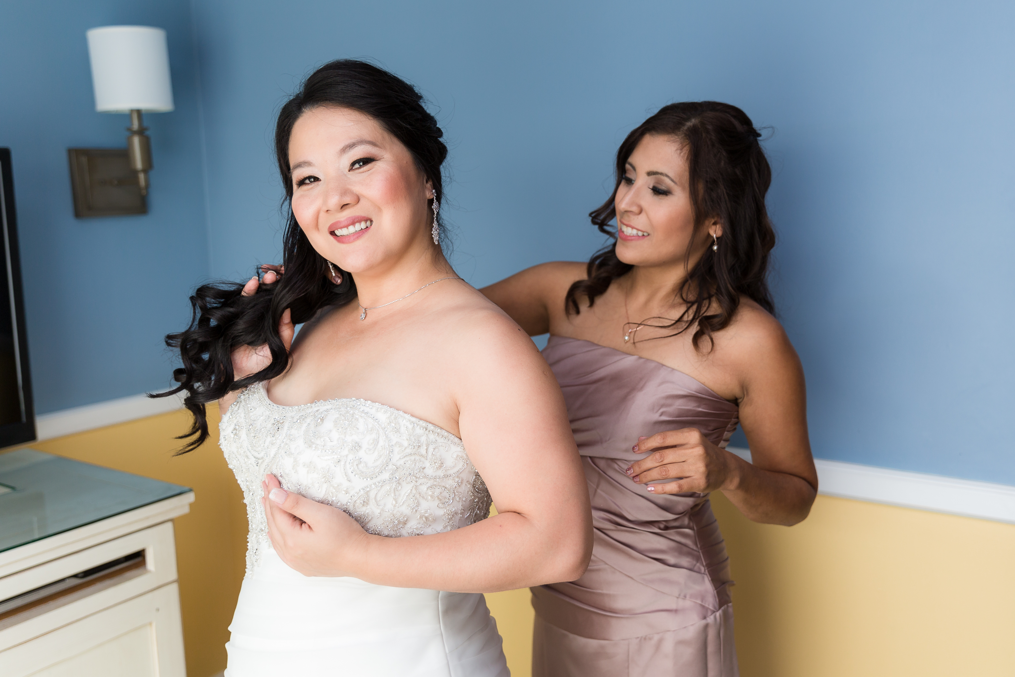 Bride putting on jewelry with maid of honor