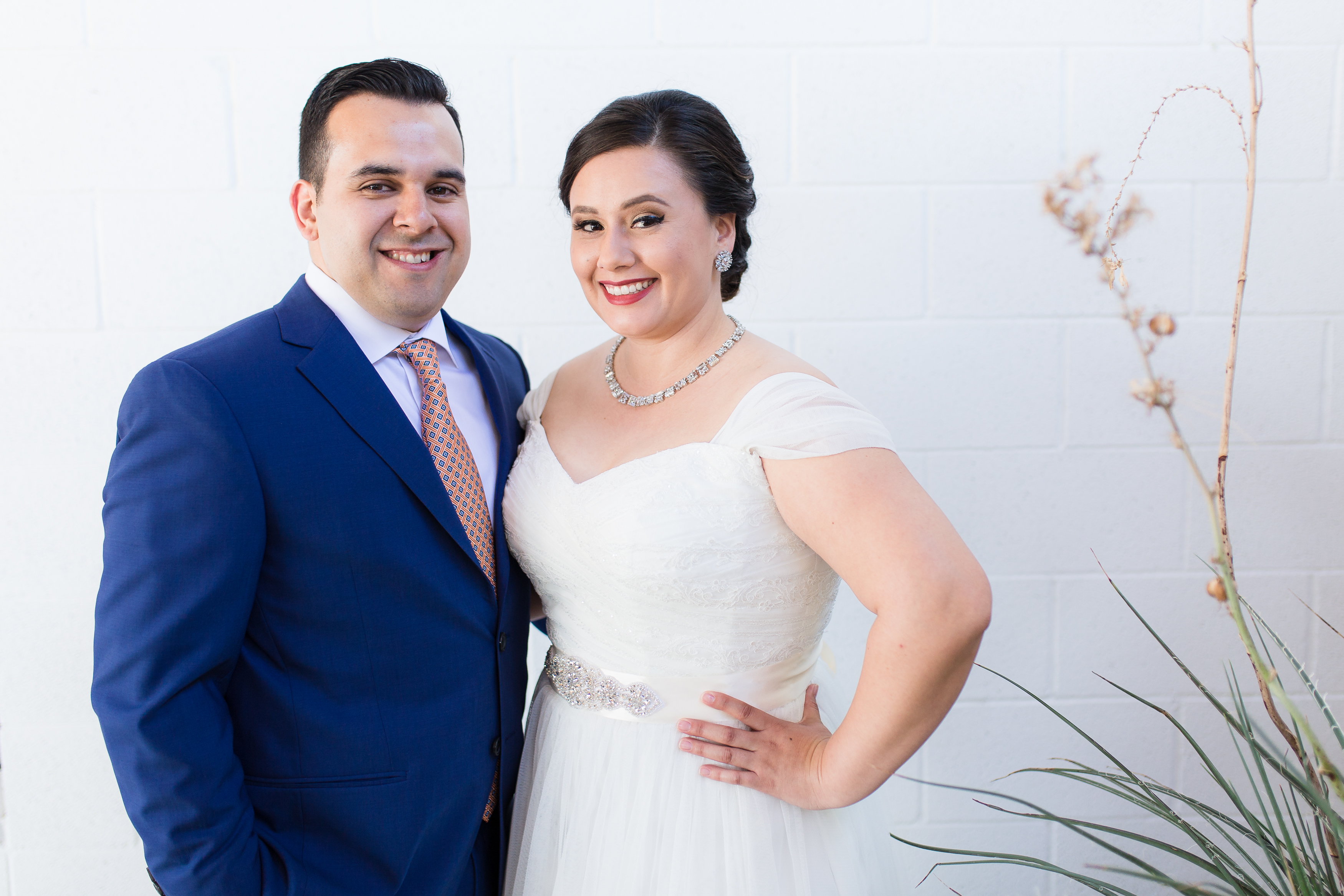 Wedding couple smiling at camera against plain white wall
