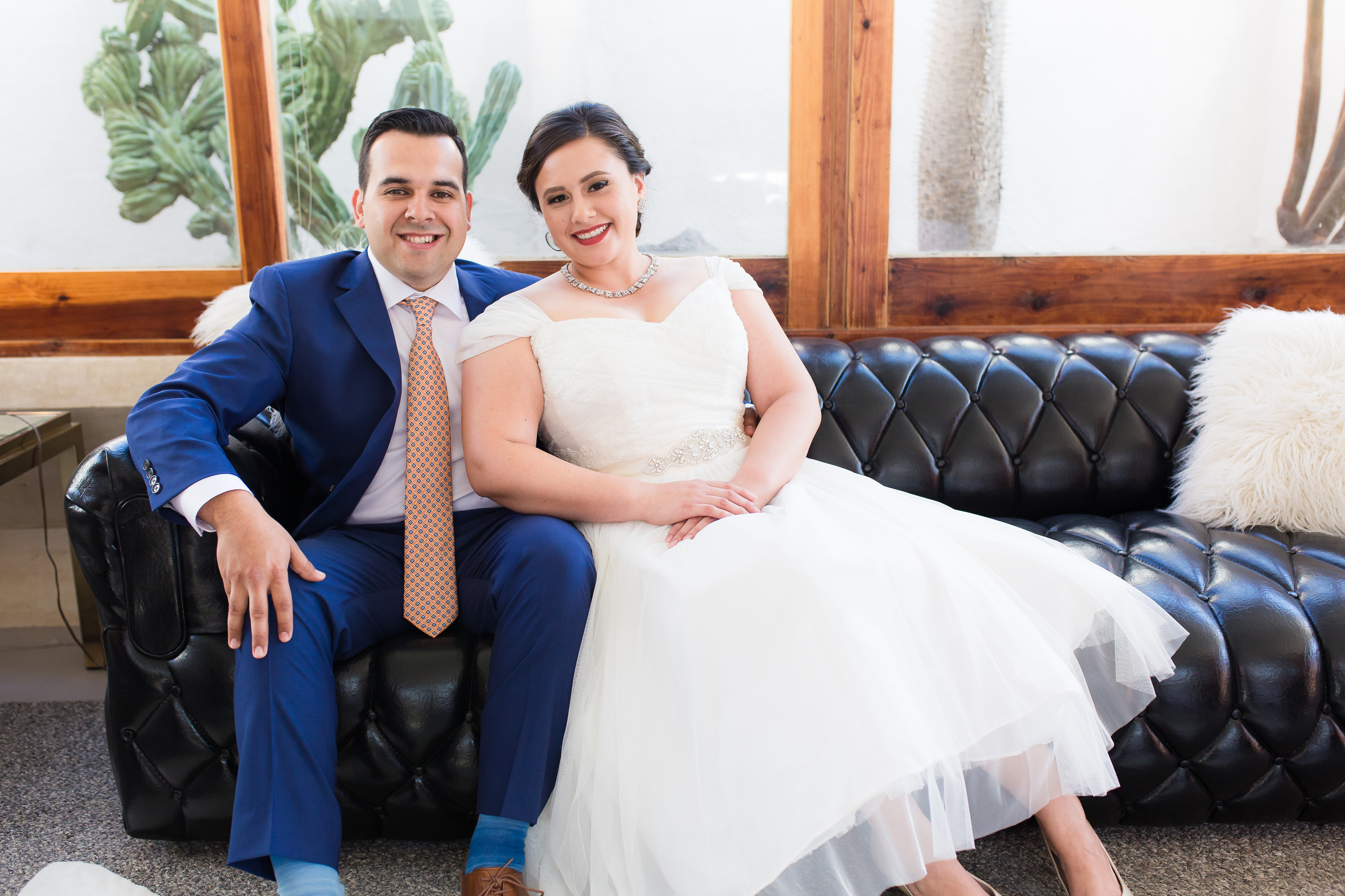 Sweethearts cuddle on leather couch in wedding attire, by Stefani Ciotti