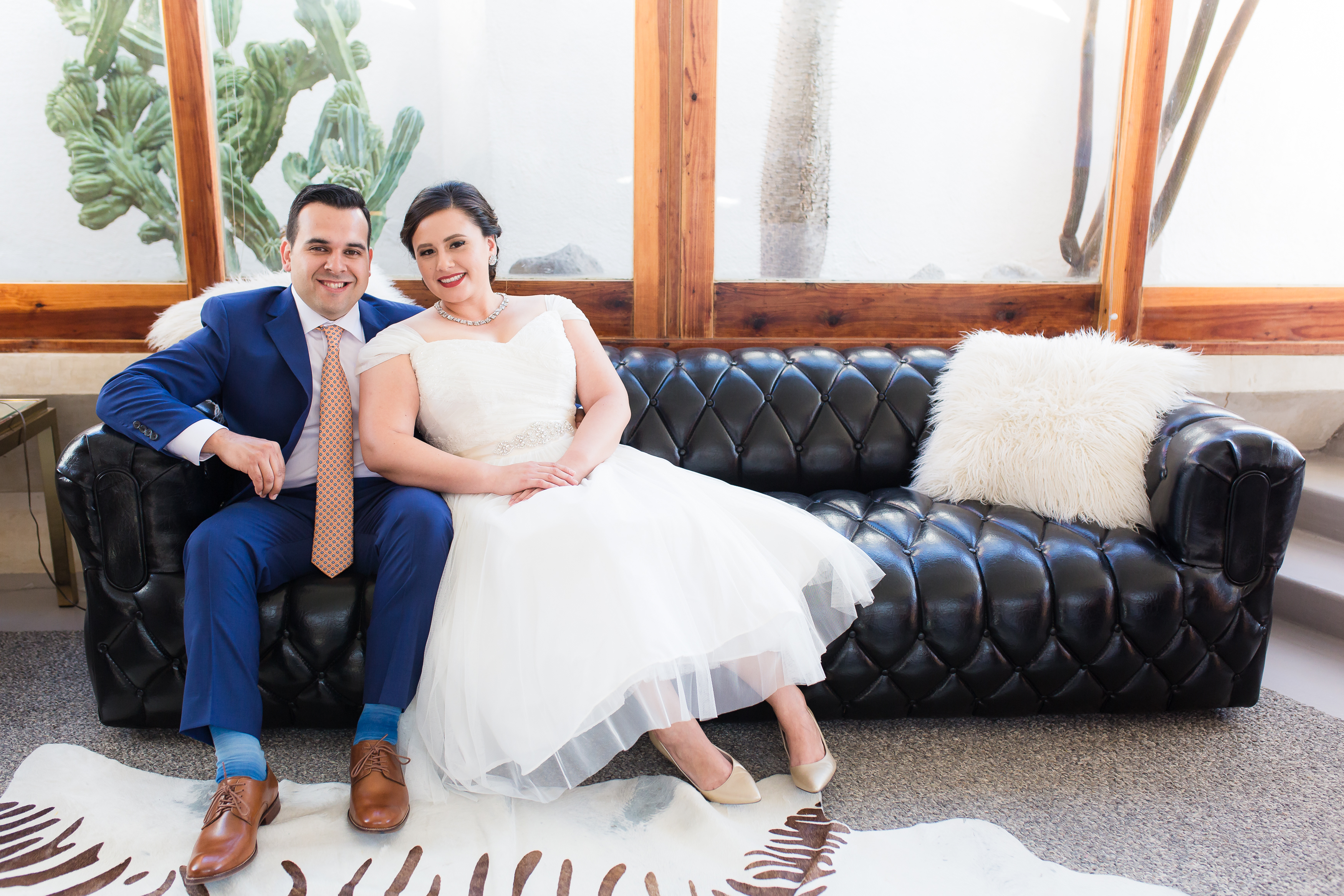 Wedding couple sitting on black leather couch in hotel room at The Lautner