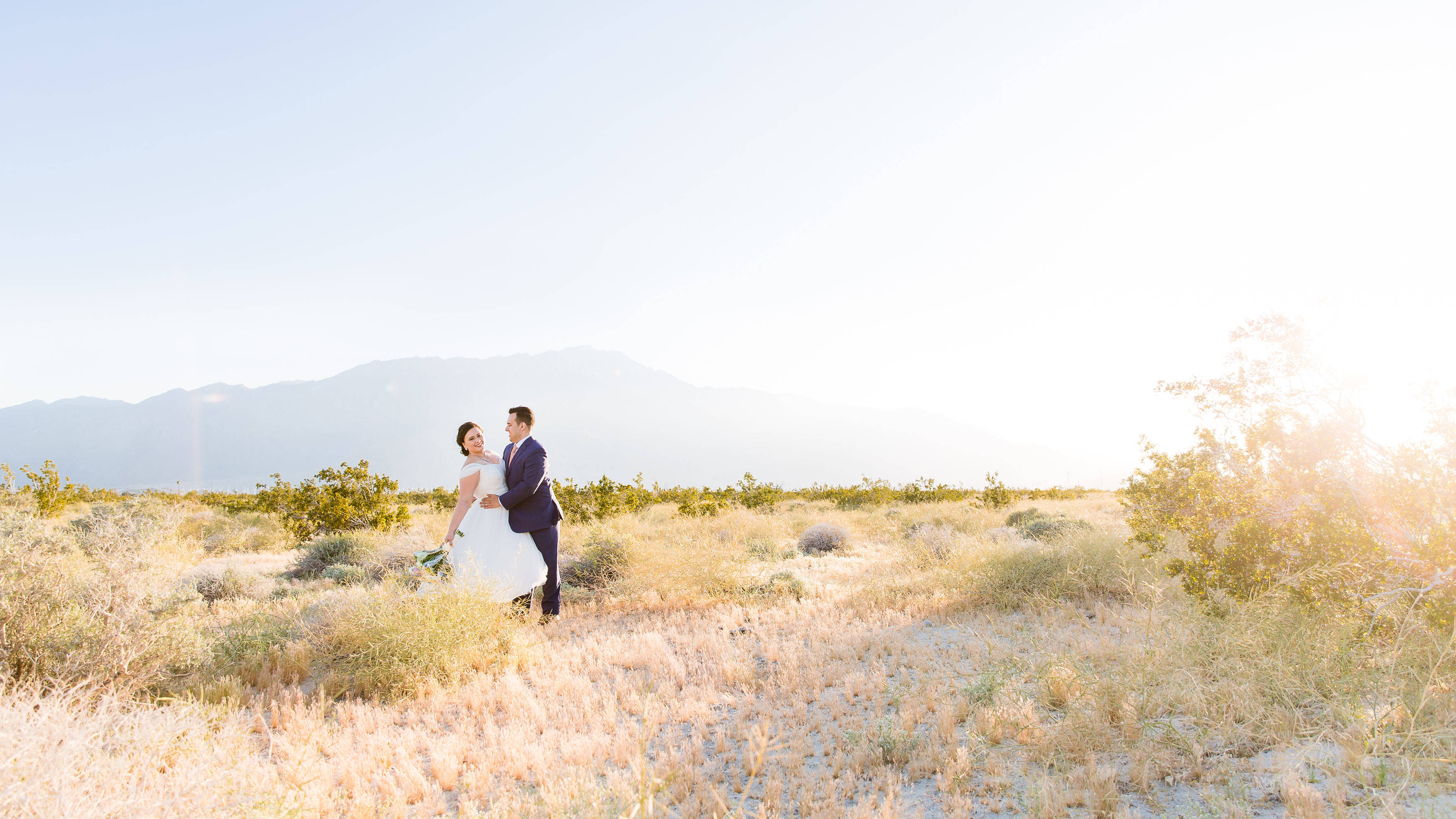 Couple dipping in the desert with mountains in background at golden hour
