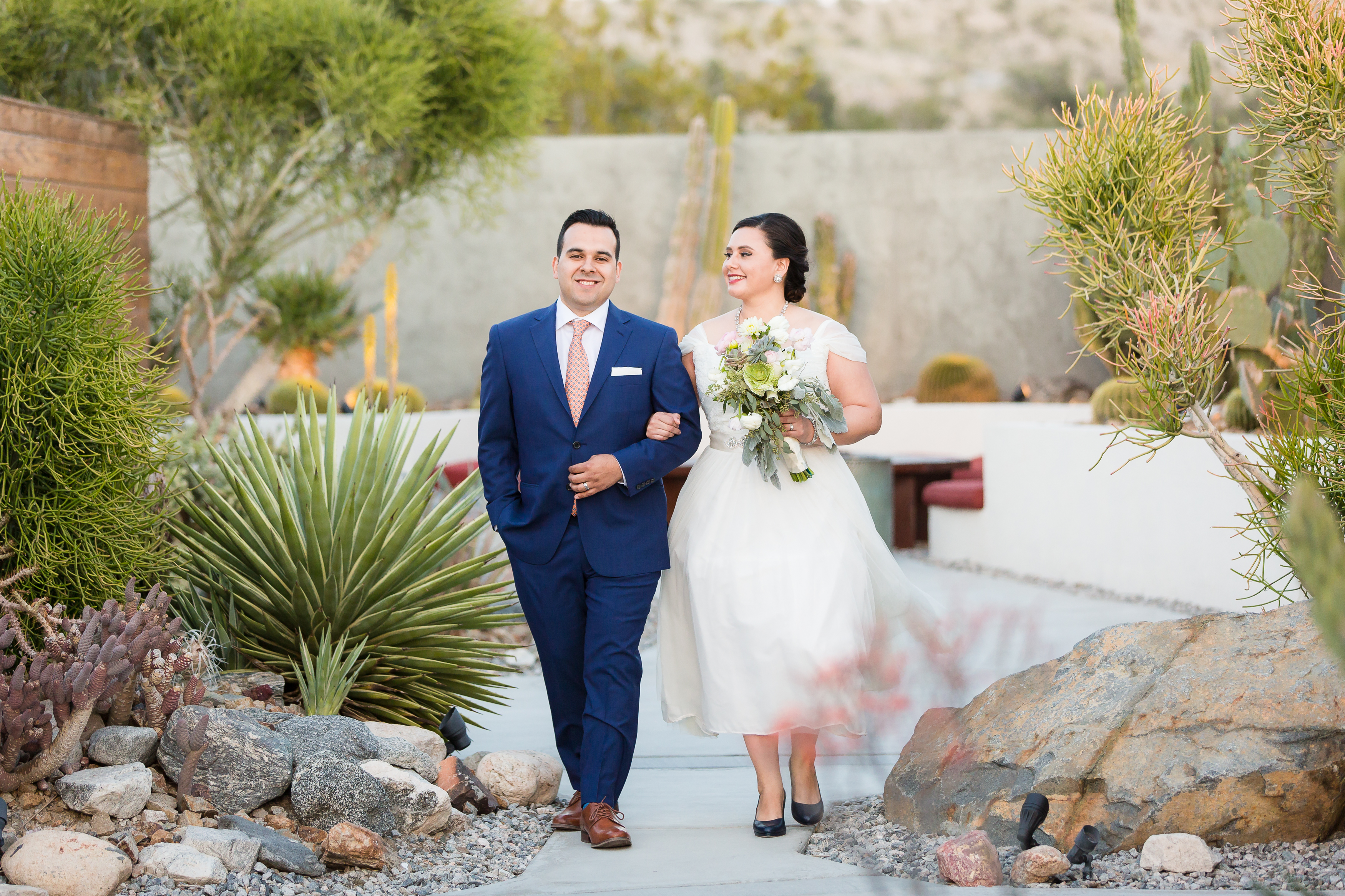 Wedding couple linking arms walking hotel grounds in Desert Hot Springs
