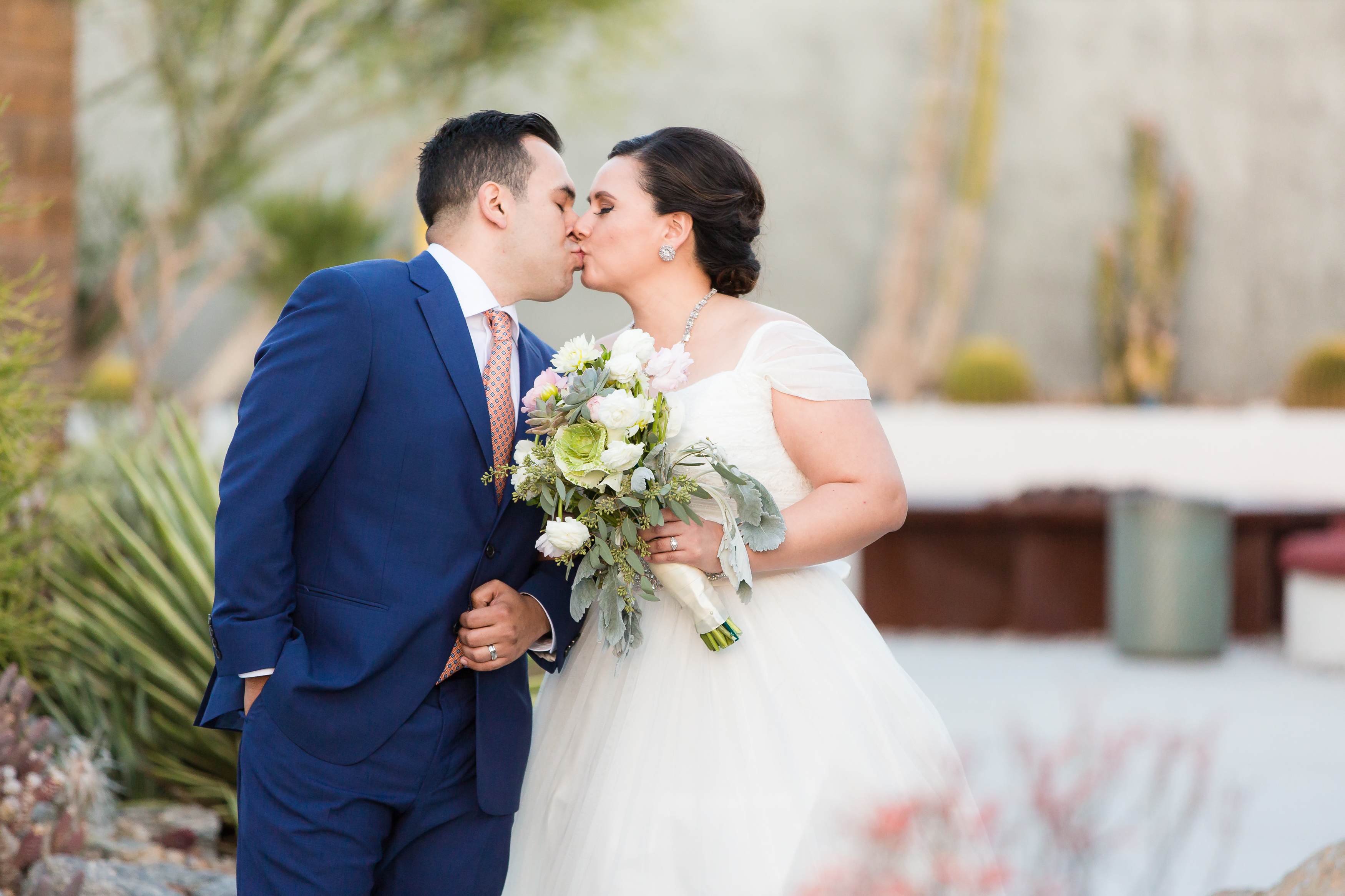 Wedding couple kissing while holding succulent wedding bouquet