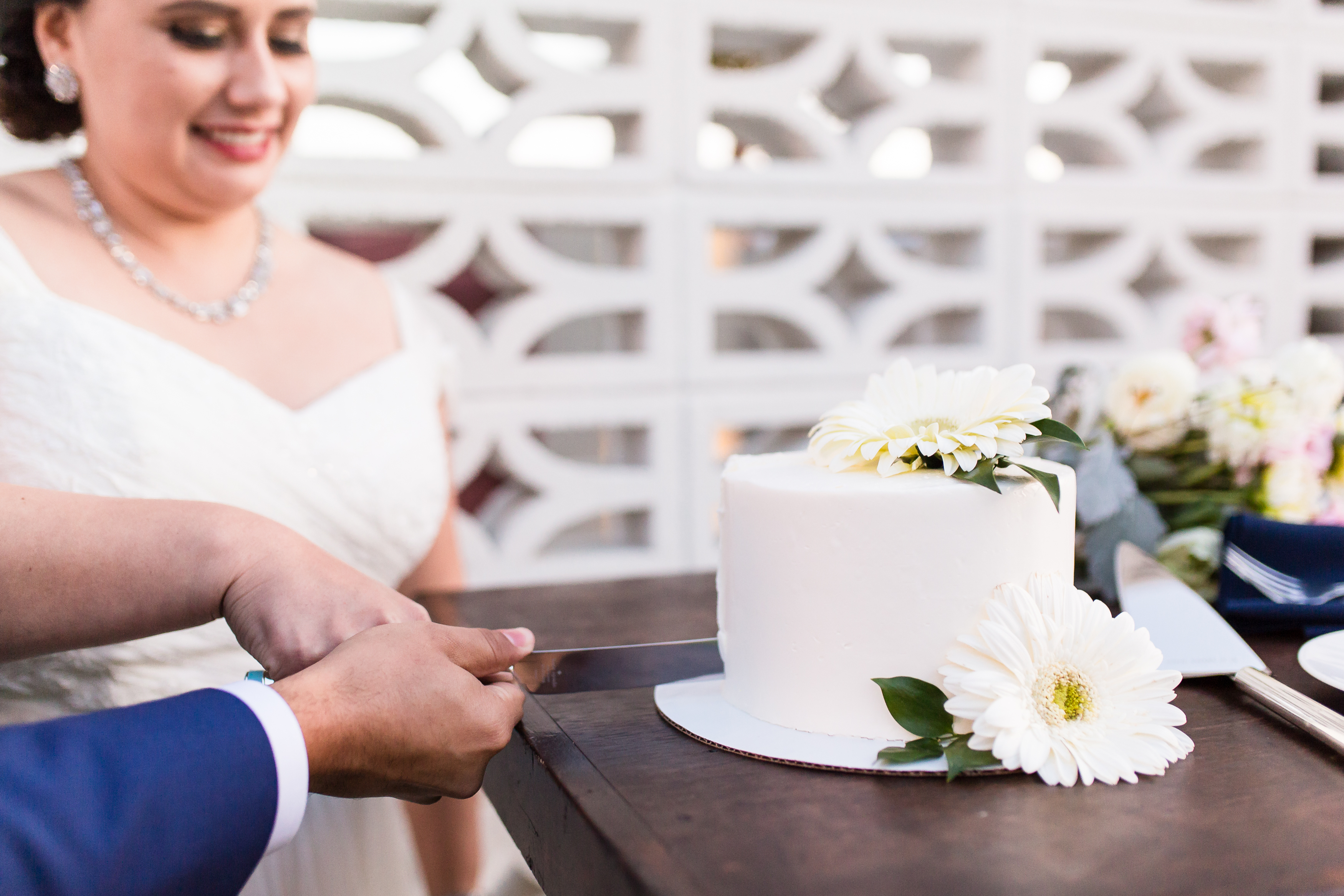 Couple cutting white wedding cake with knife