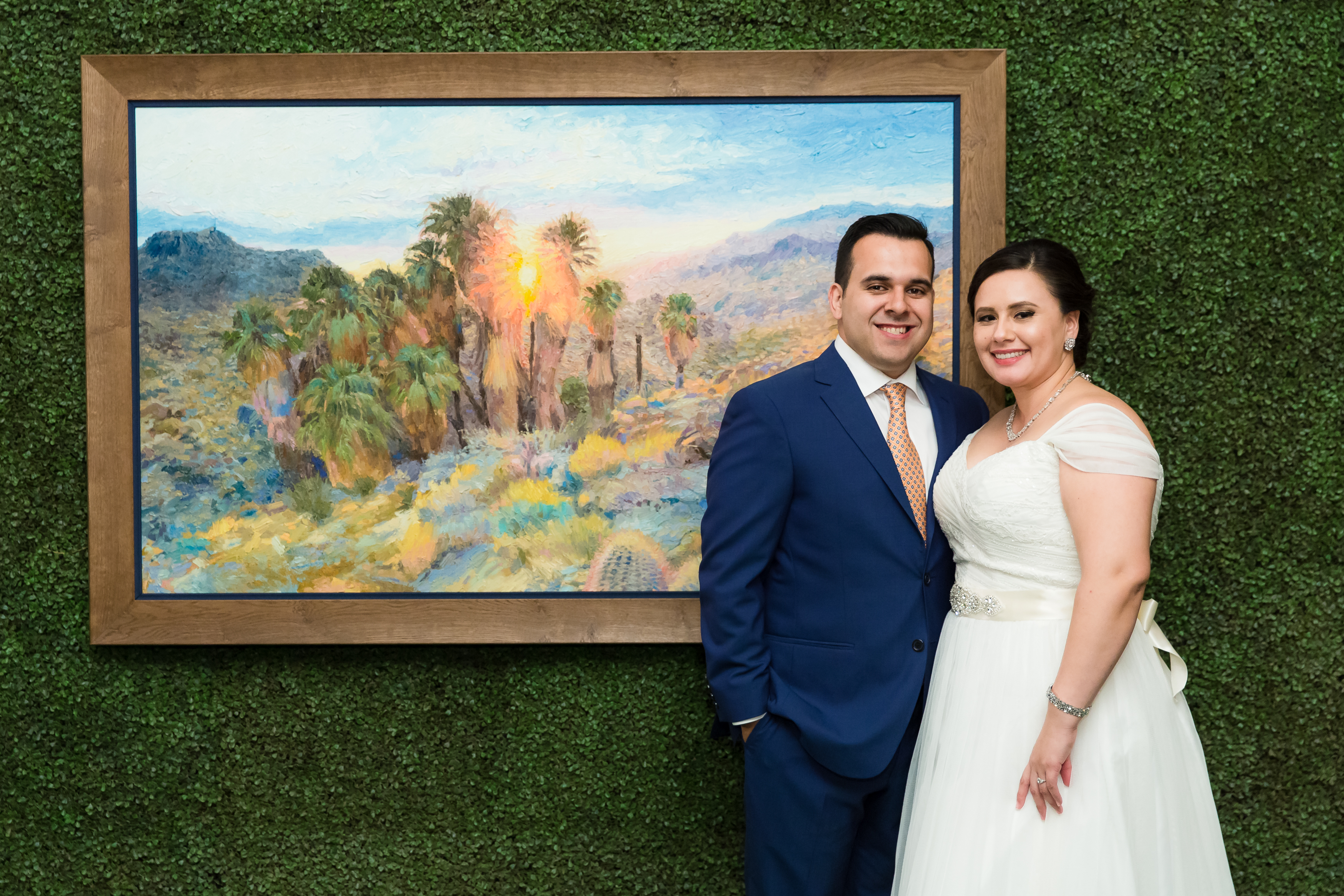 Wedding couple standing next to commissioned painting of the desert in CA