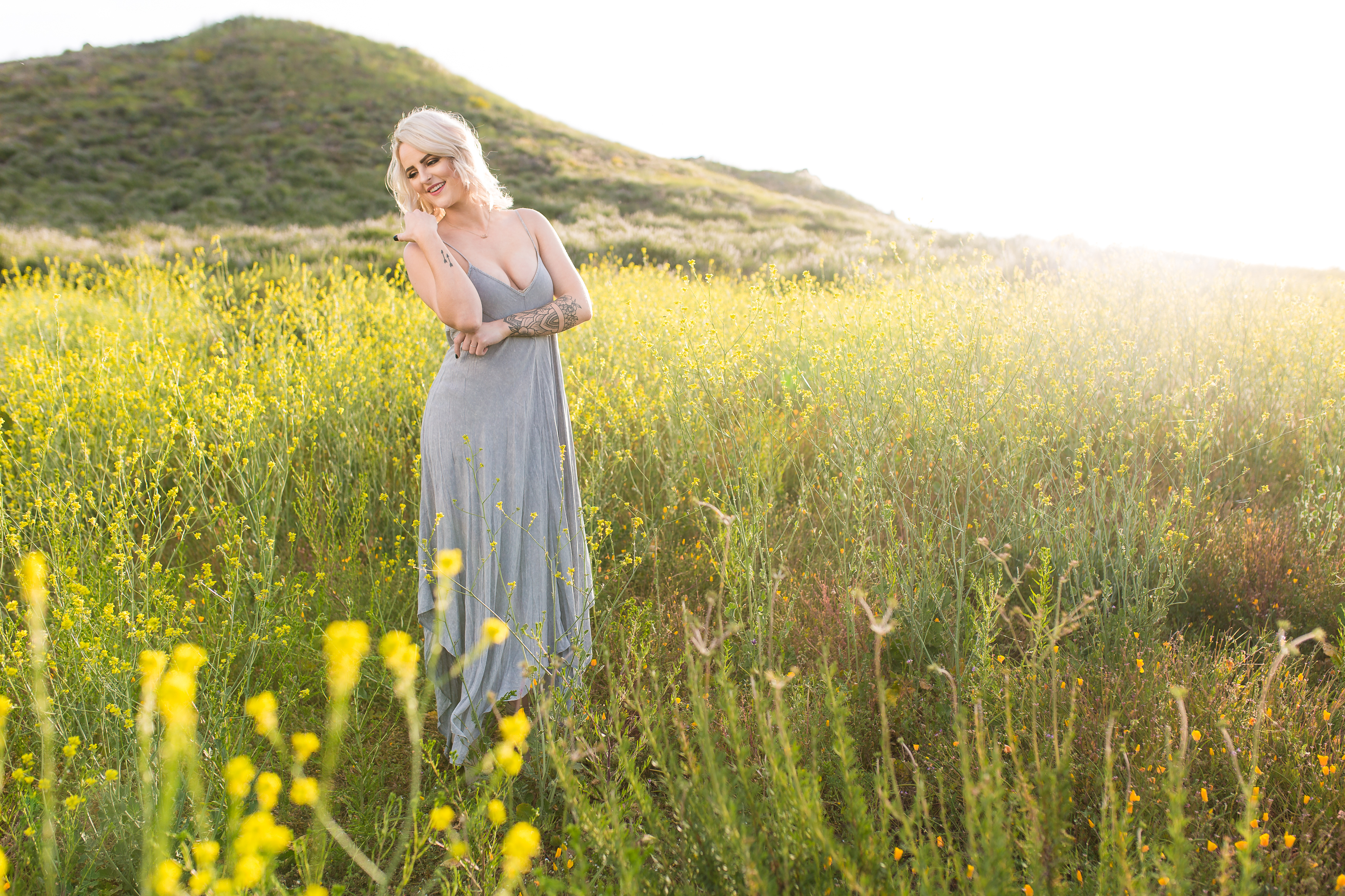 Girl in dress standing in field of yellow poppies at sunrise in Lake Elsinore