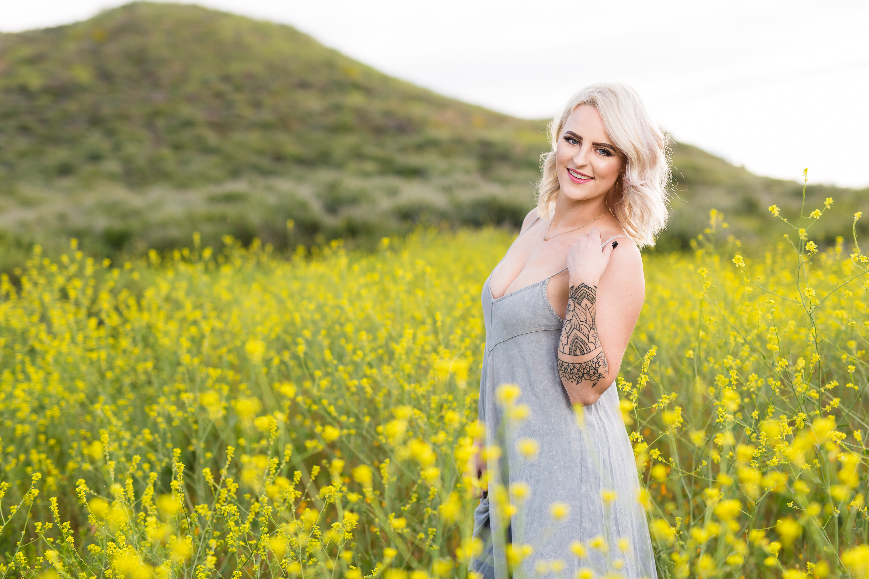 Woman with sultry smile standing in field of yellow poppies