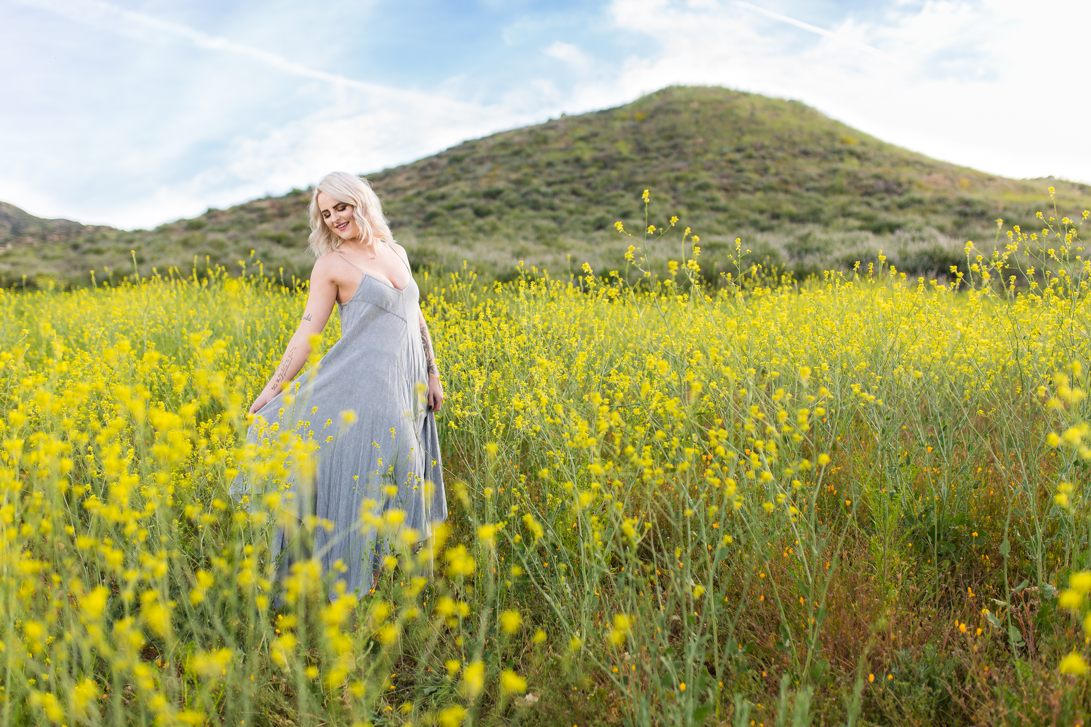Beautiful tattooed girl playing with dress in flower field