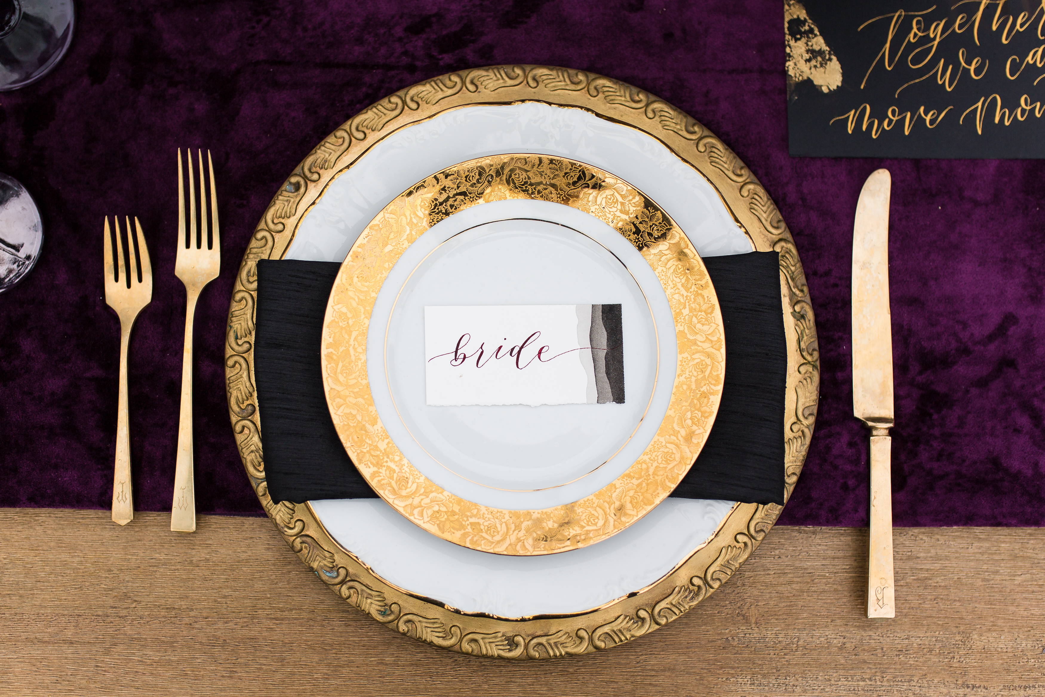 Golden lined bridal plates with purple drapery
