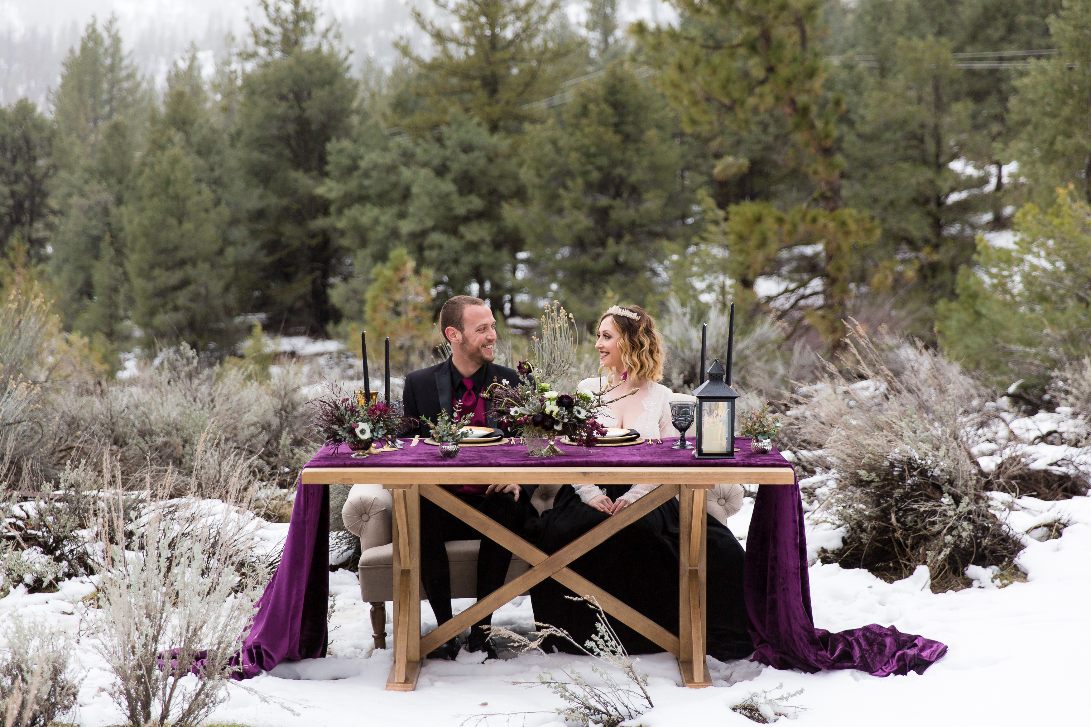 Married couple smiling at each other at sweetheart table in snow