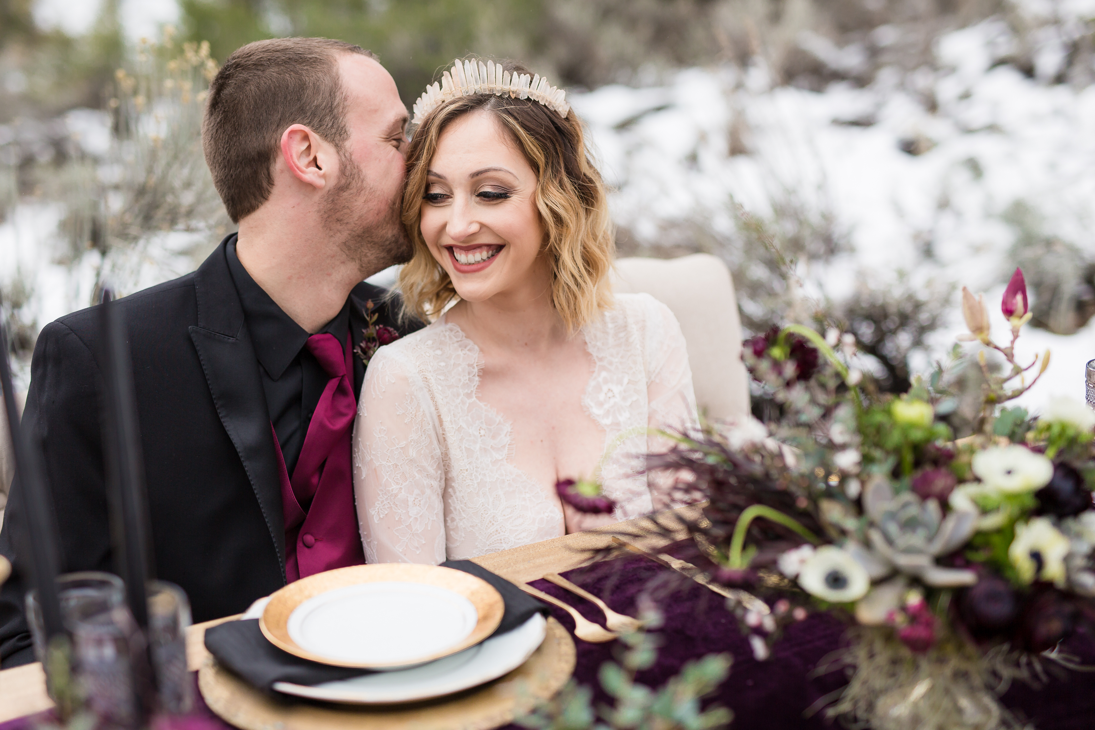 Groom whispering in bride's ear at reception table in winter