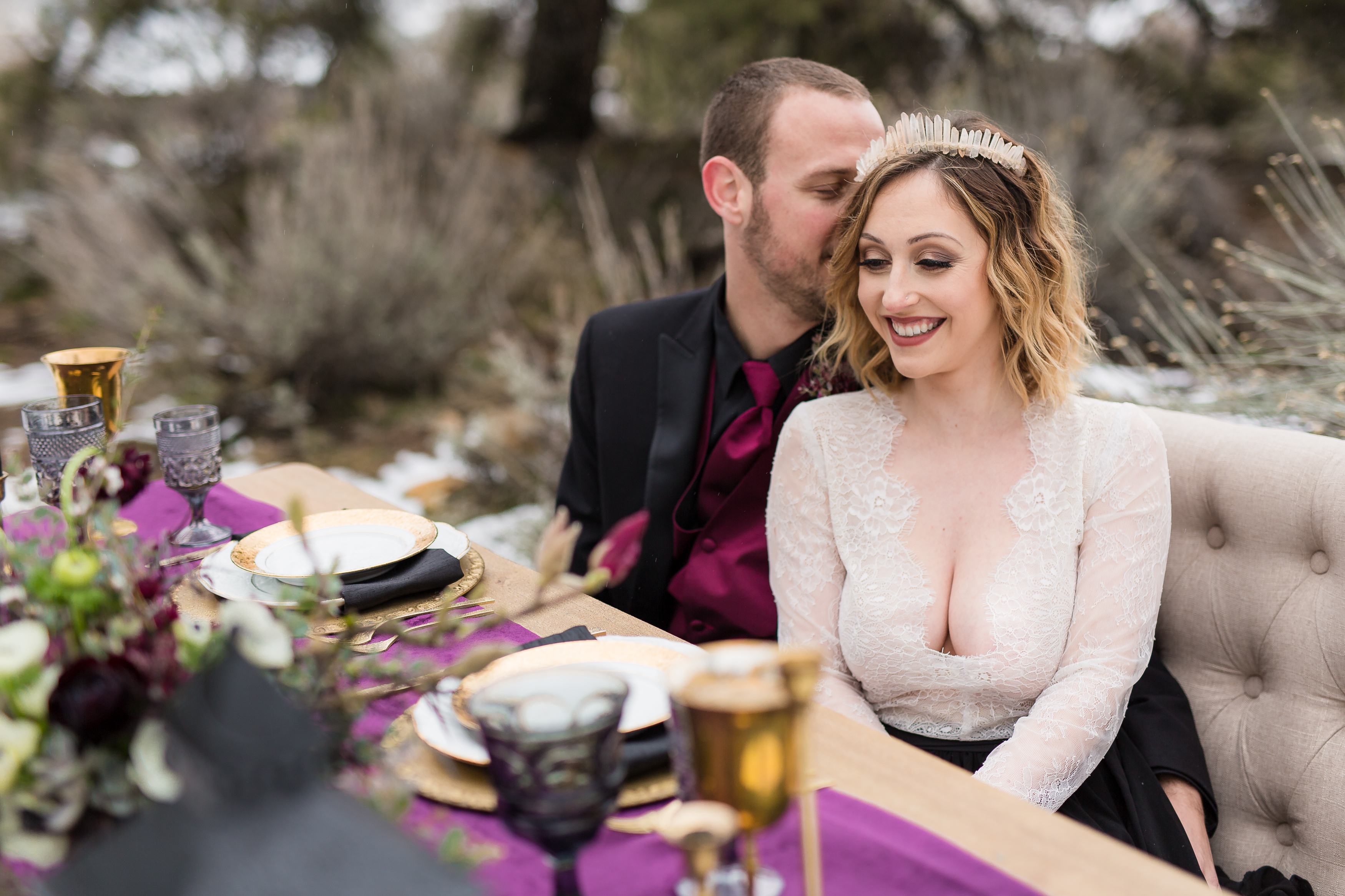 Man whispering into woman's ear on couch by sweetheart table
