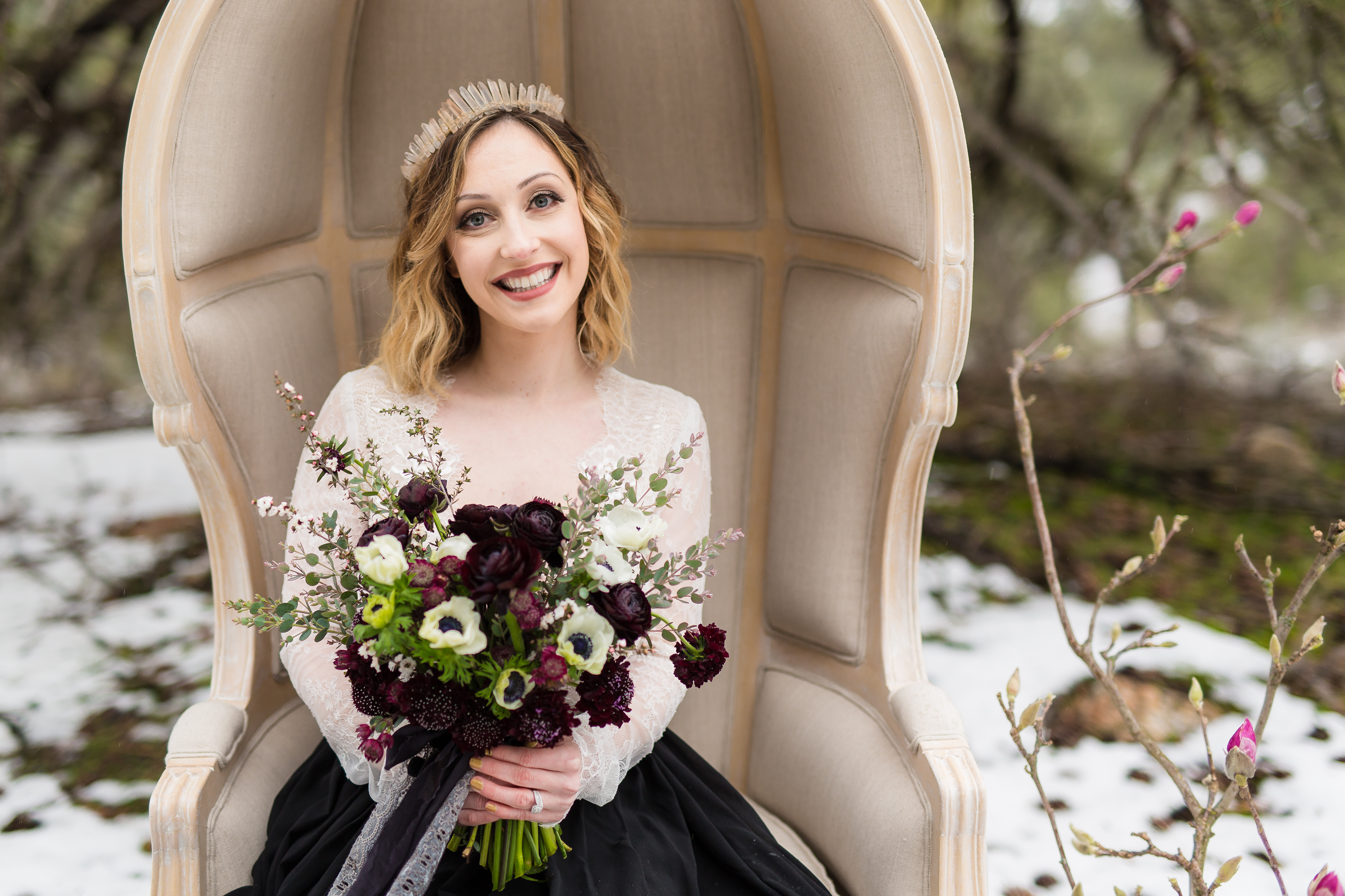 Beautiful bride holding wedding bouquet and sitting in a beige chair