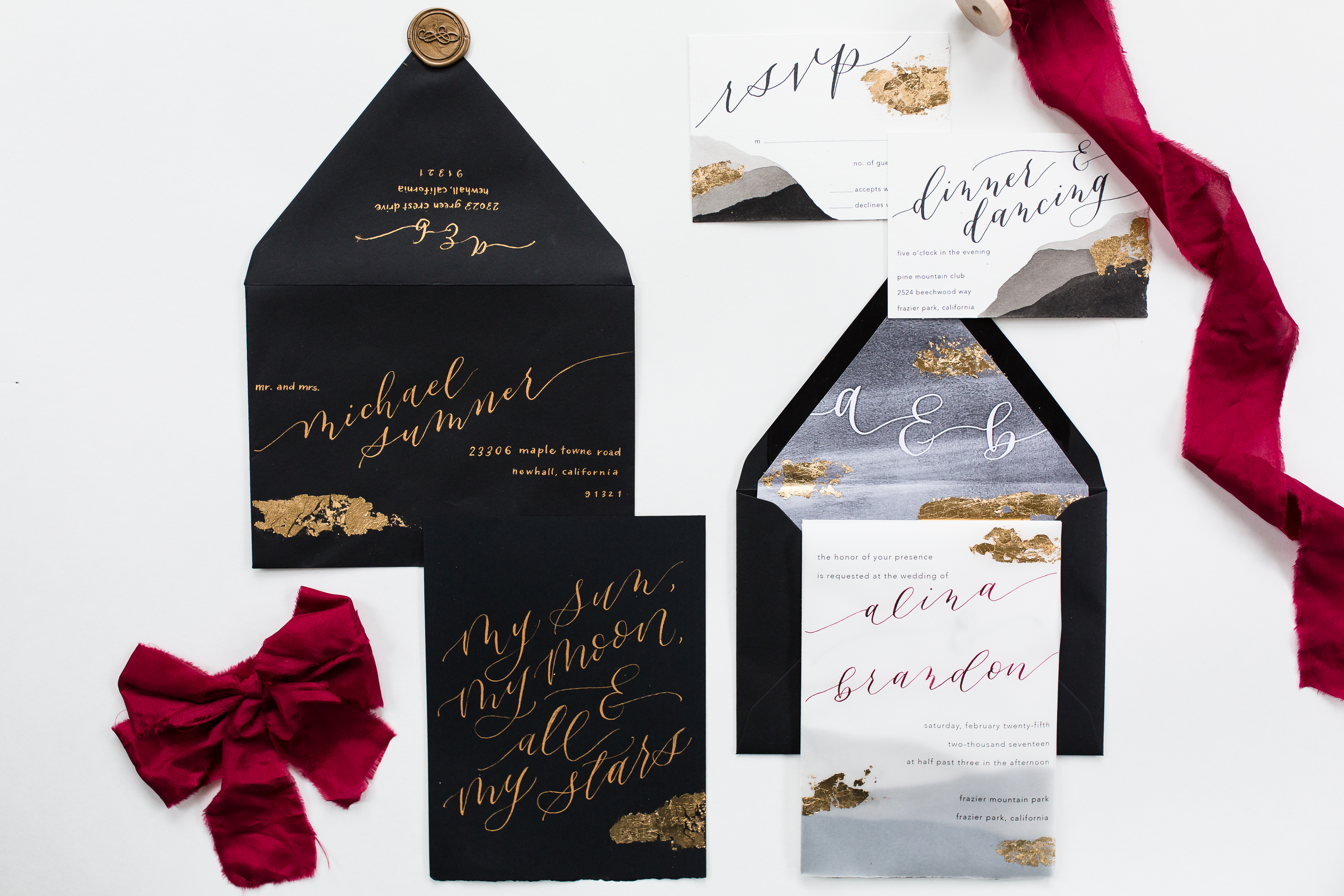 Moody black wedding stationery with gold text and red ribbon