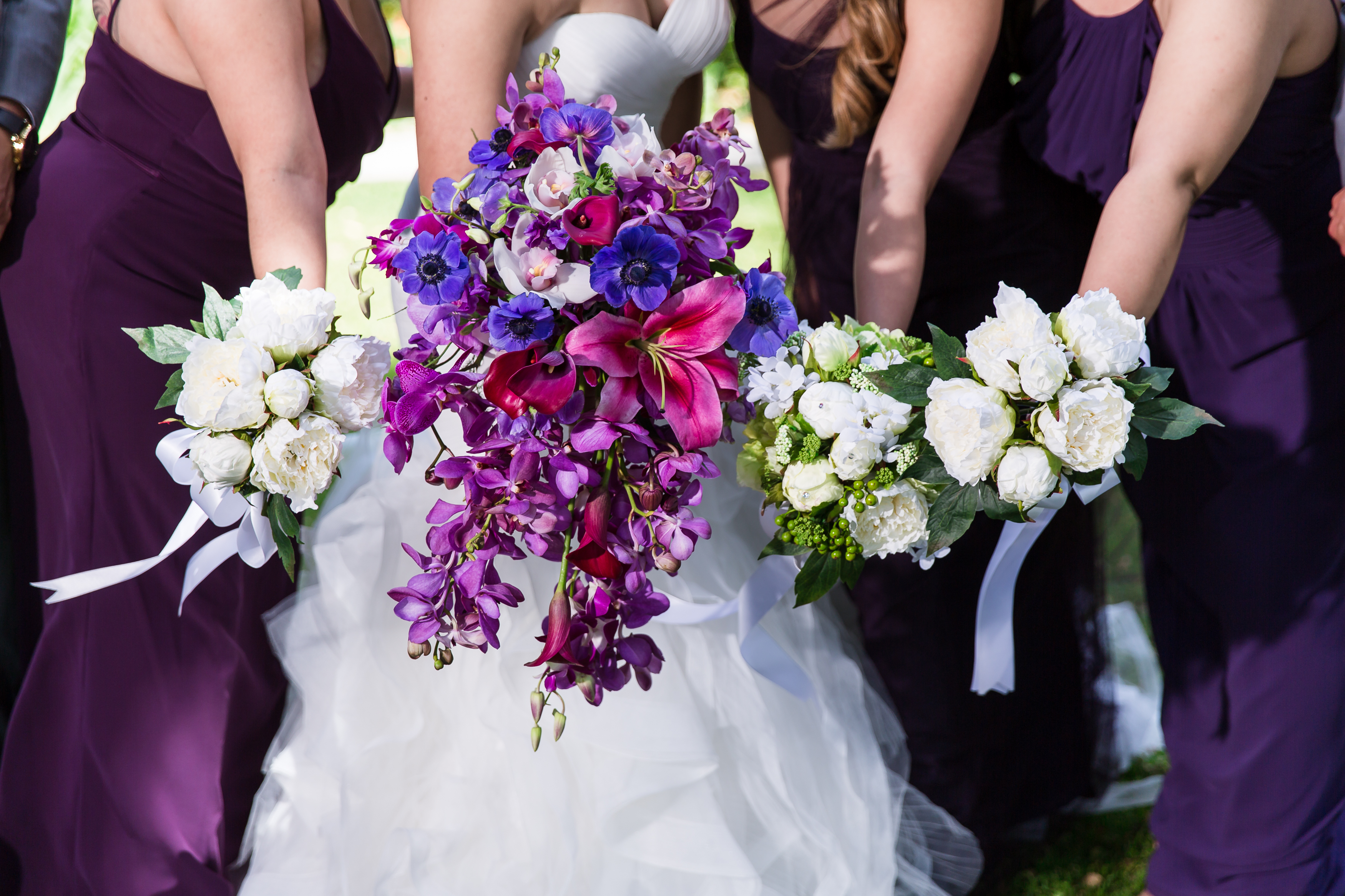 Bride and bridesmaids holding out purple wedding bouquets