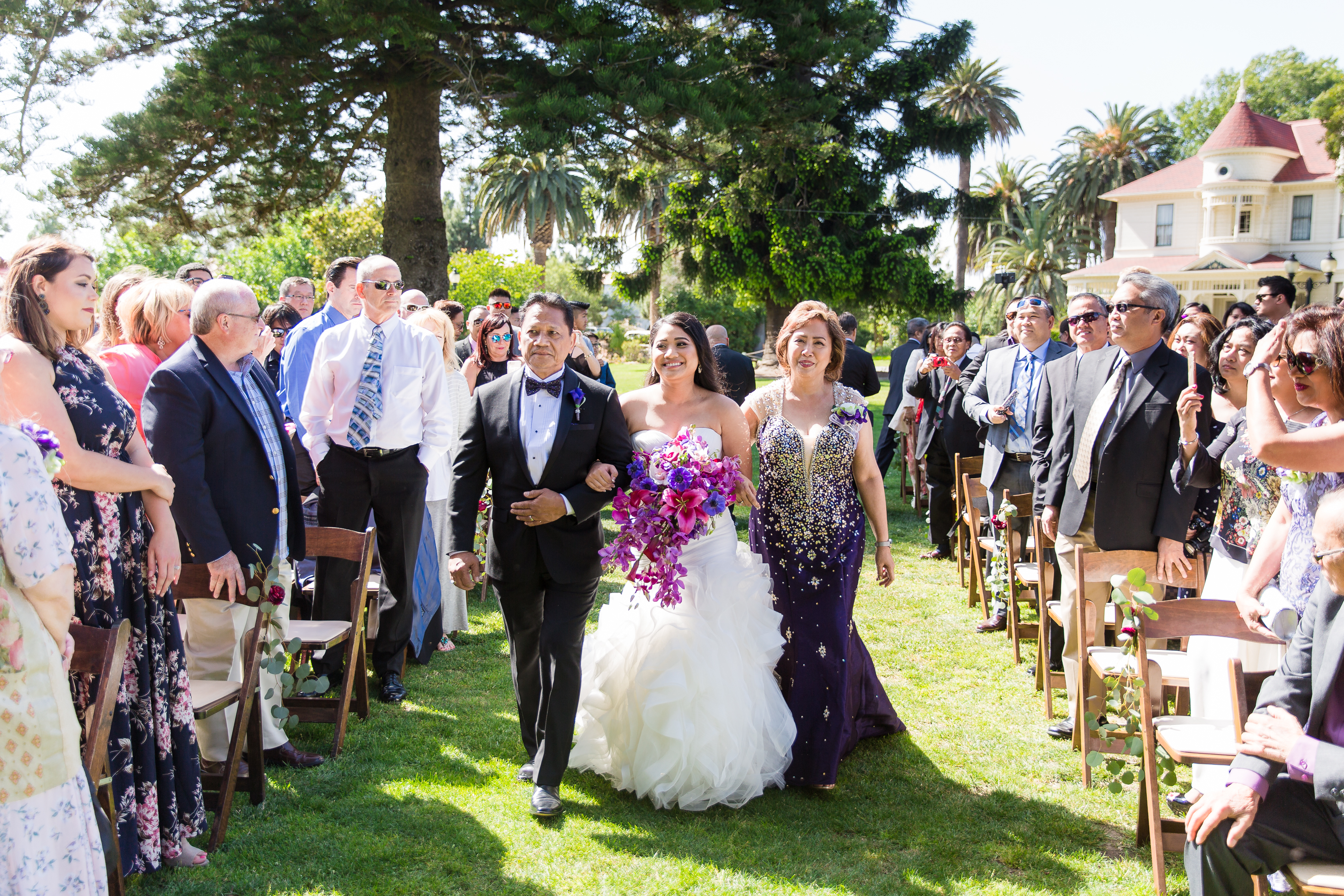 Bride's parents walk her down the aisle of outdoor ceremony