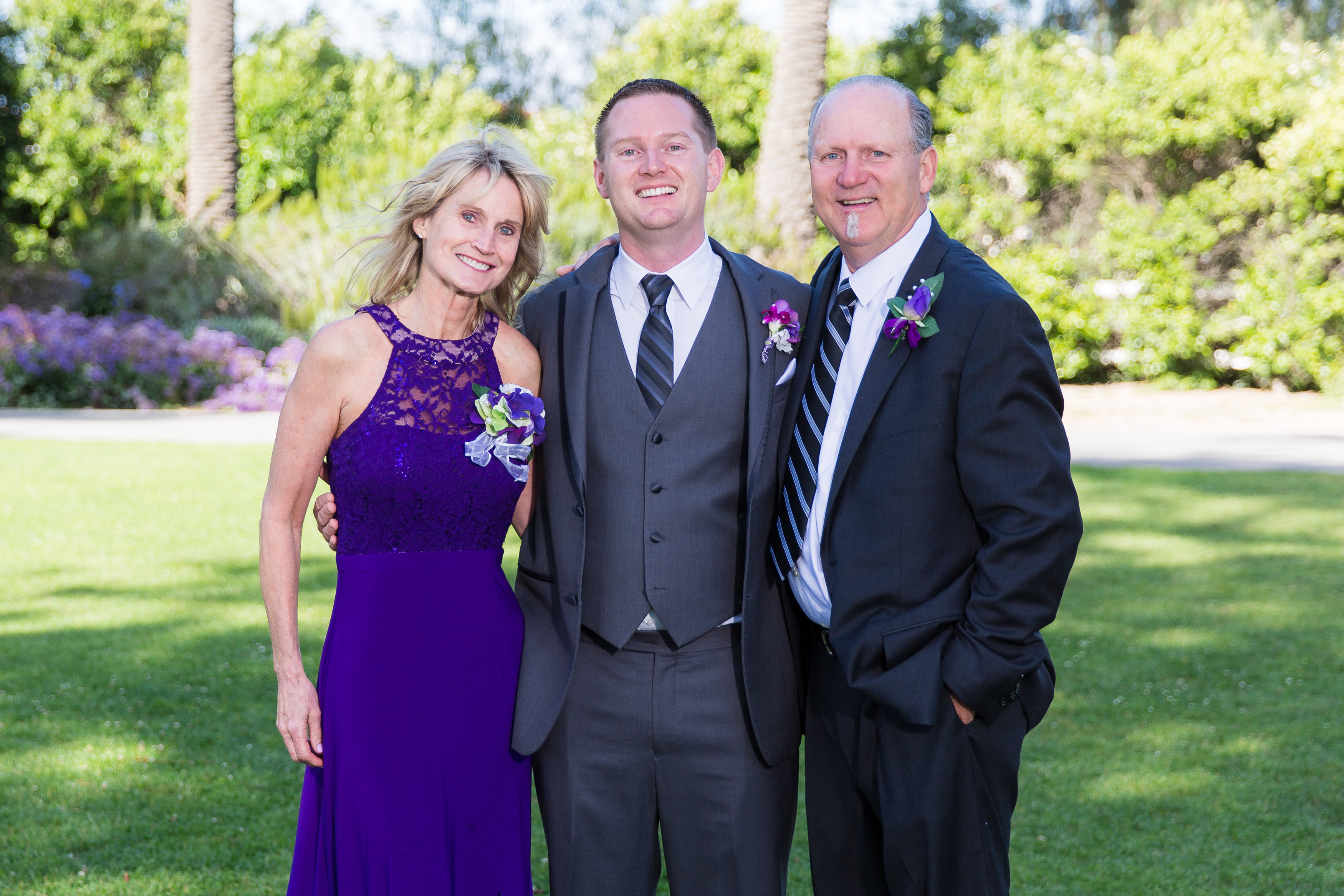 Groom with smiling parents on lawn