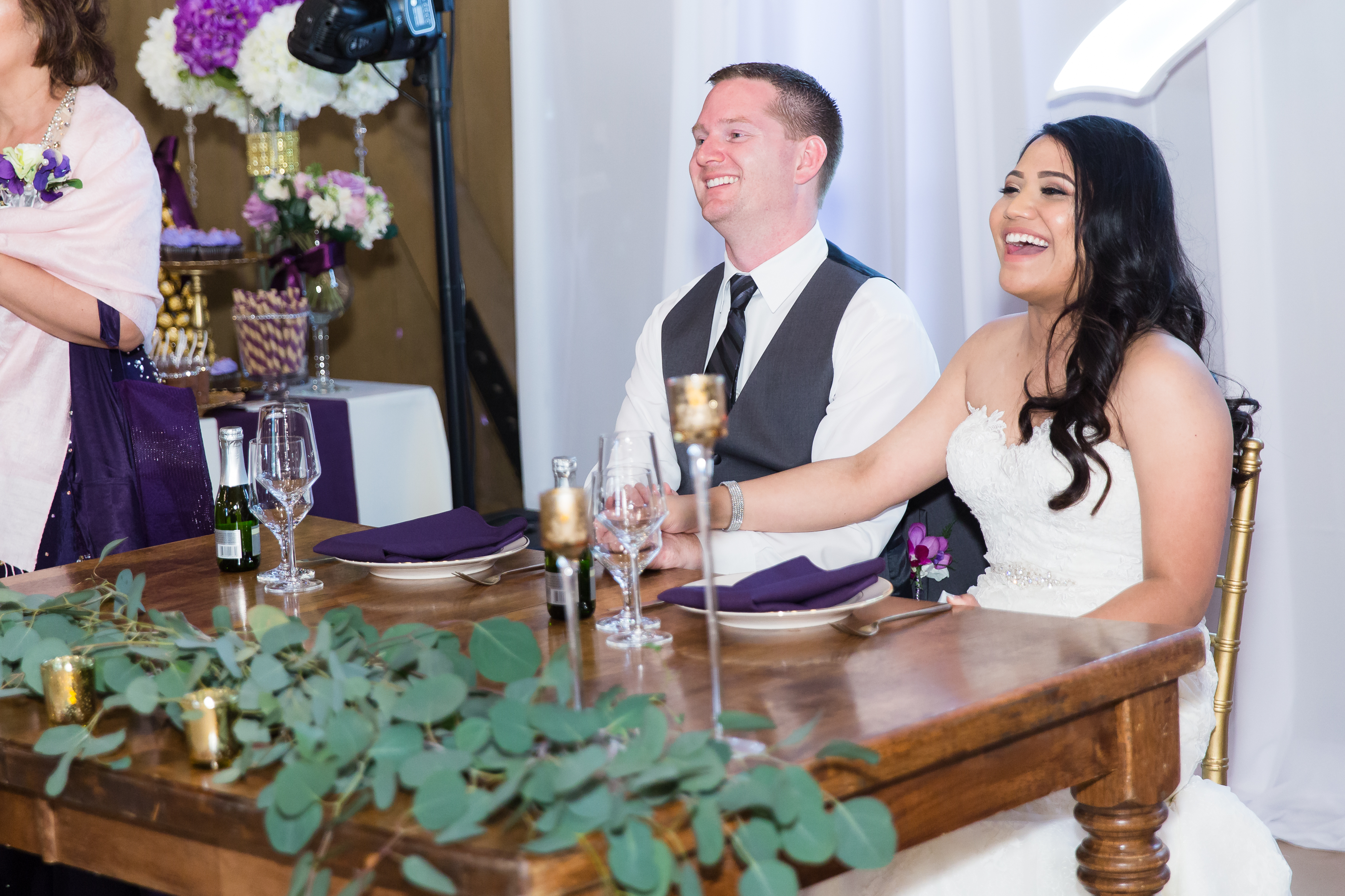 Bride and groom laughing at sweetheart table during reception