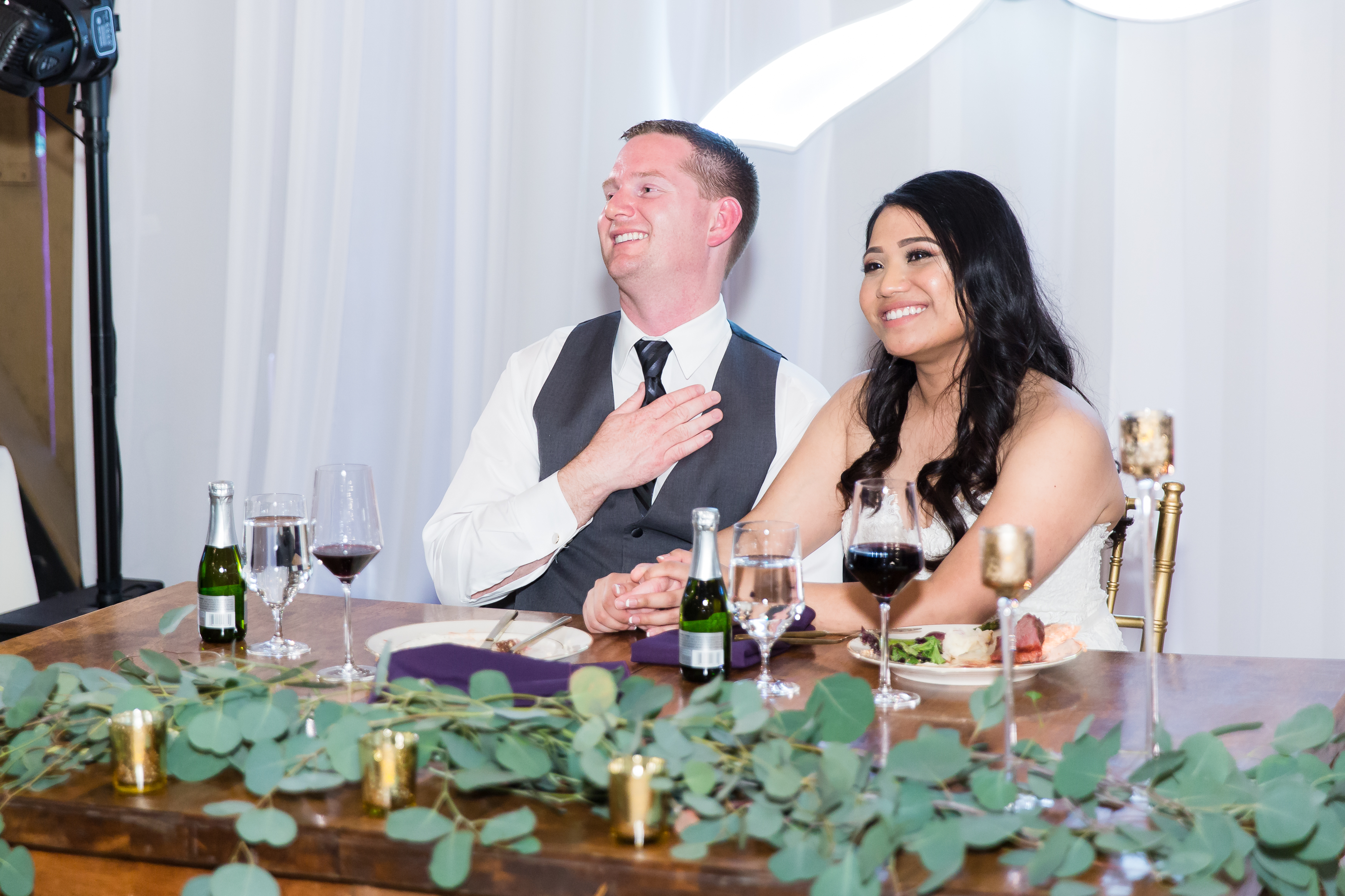 Bride and groom laughing sweetly at sweetheart table during reception