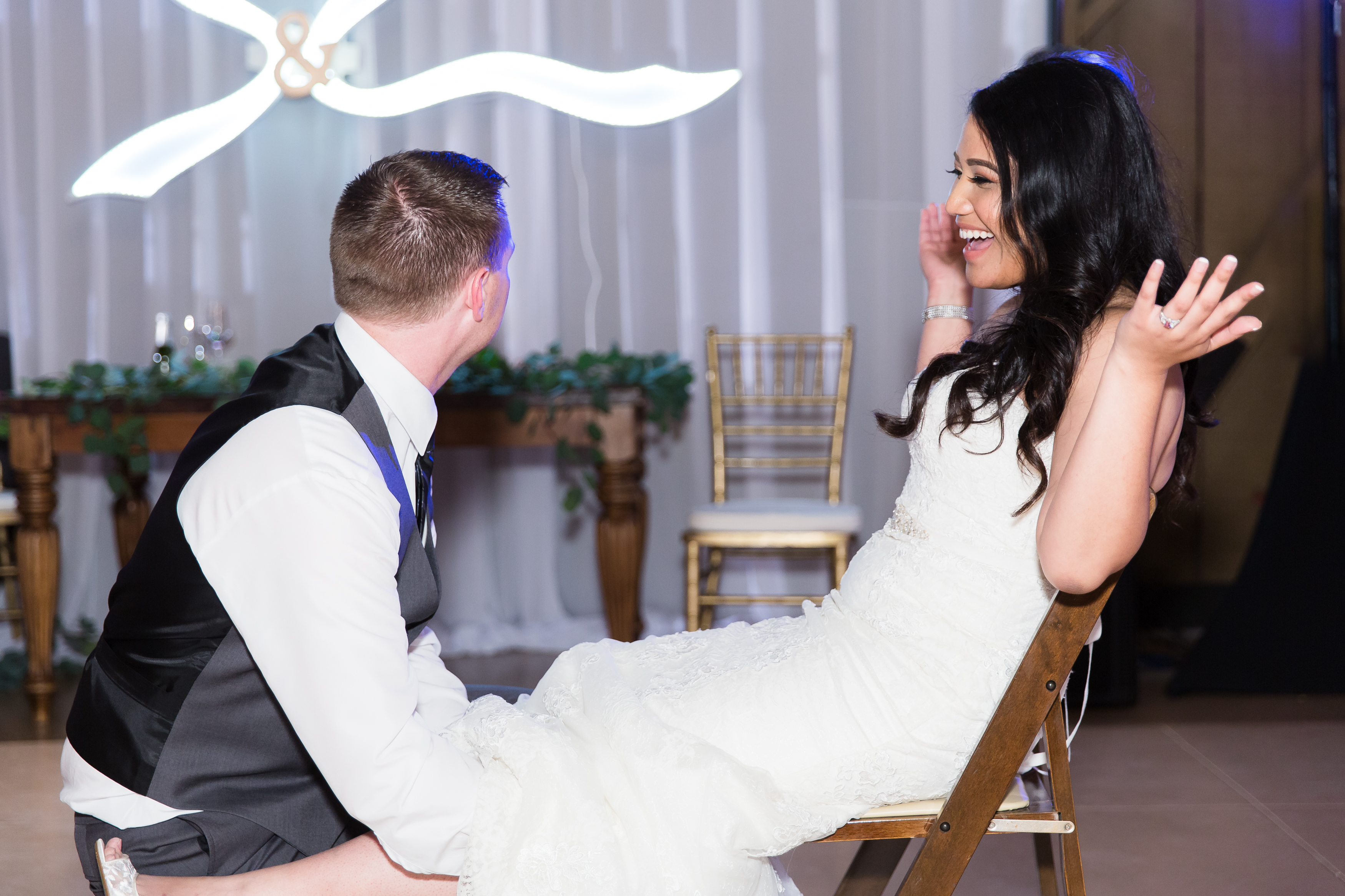 Groom removes garter while bride laughs