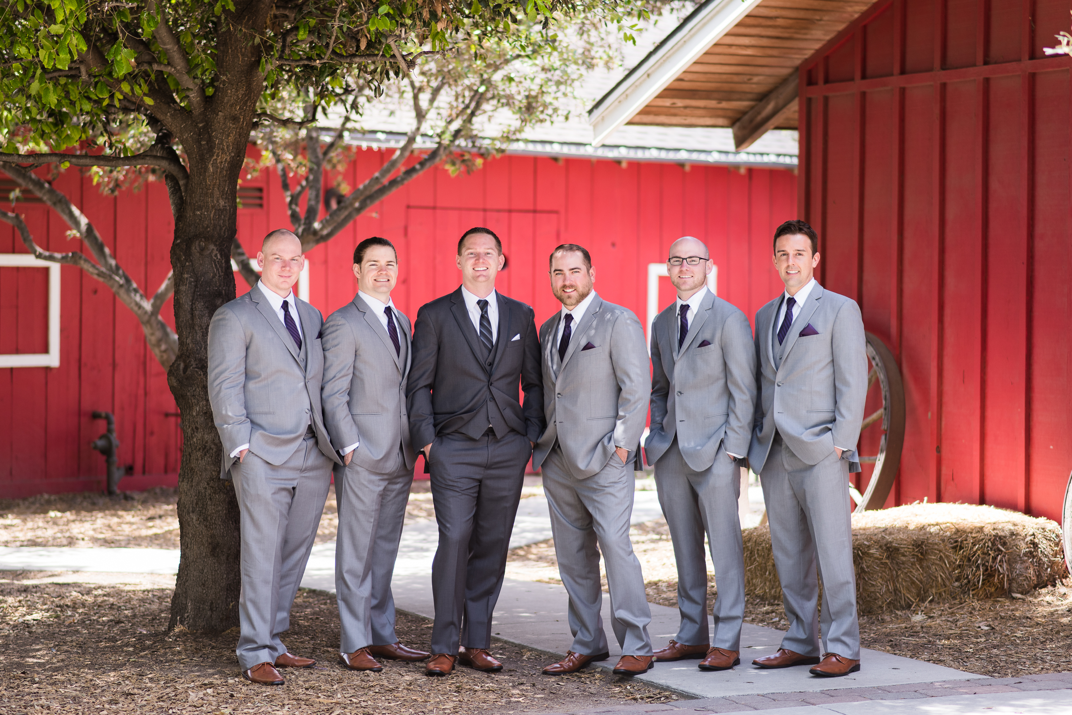 Groomsmen standing by red barn at Camarillo Ranch House