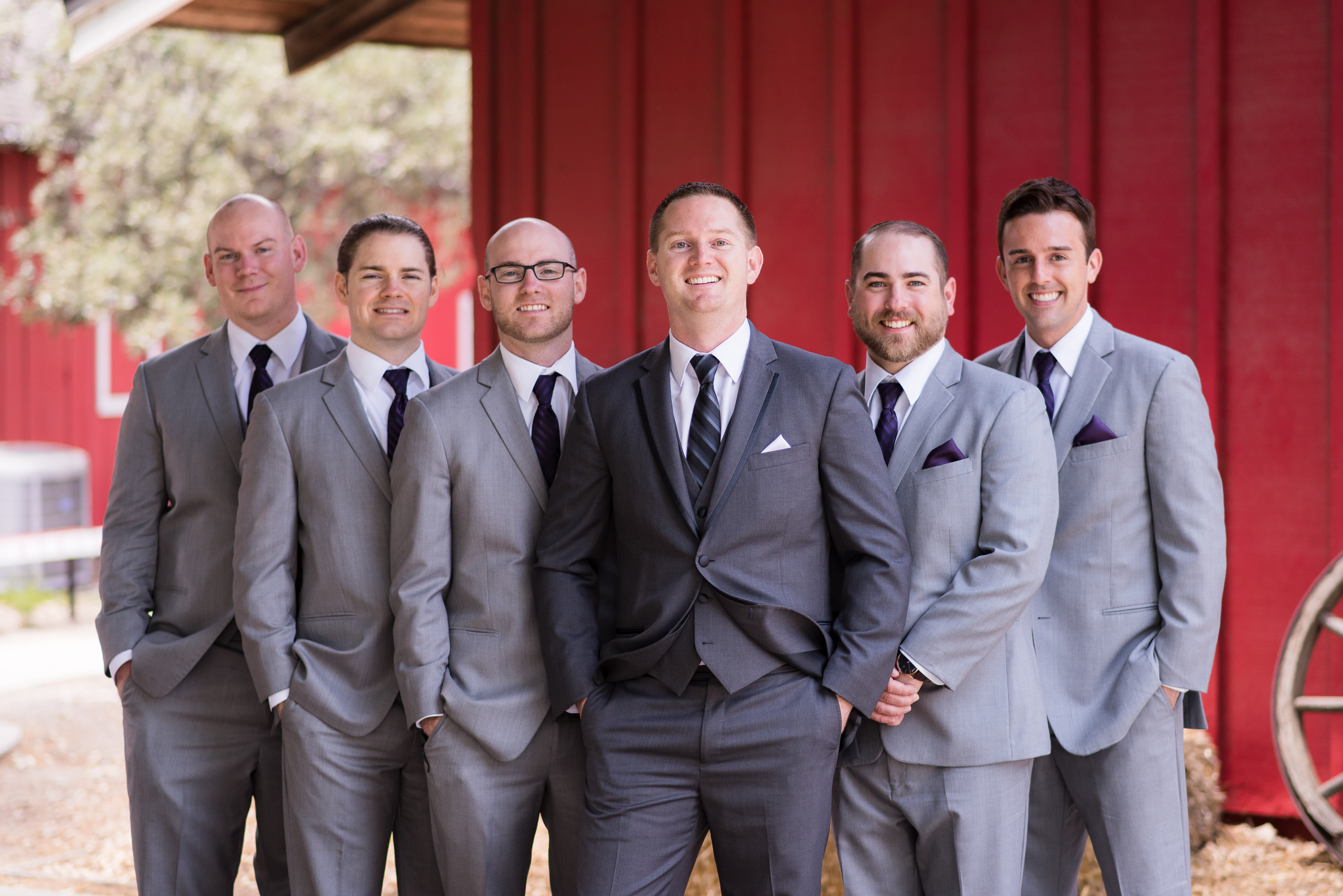 Groomsmen in grey suits standing together with hands in pockets 