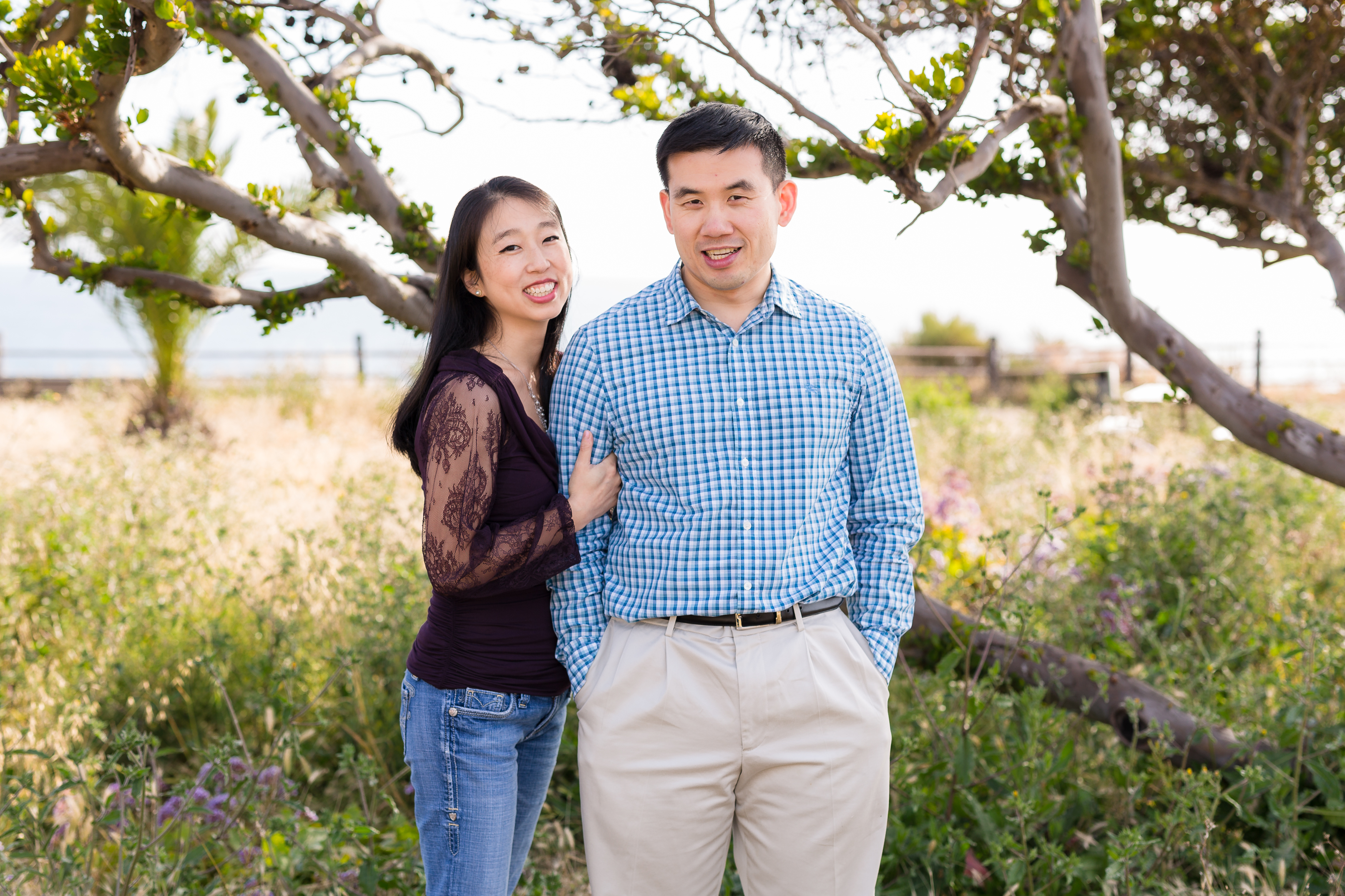 Newly engaged couple in greenery by ocean