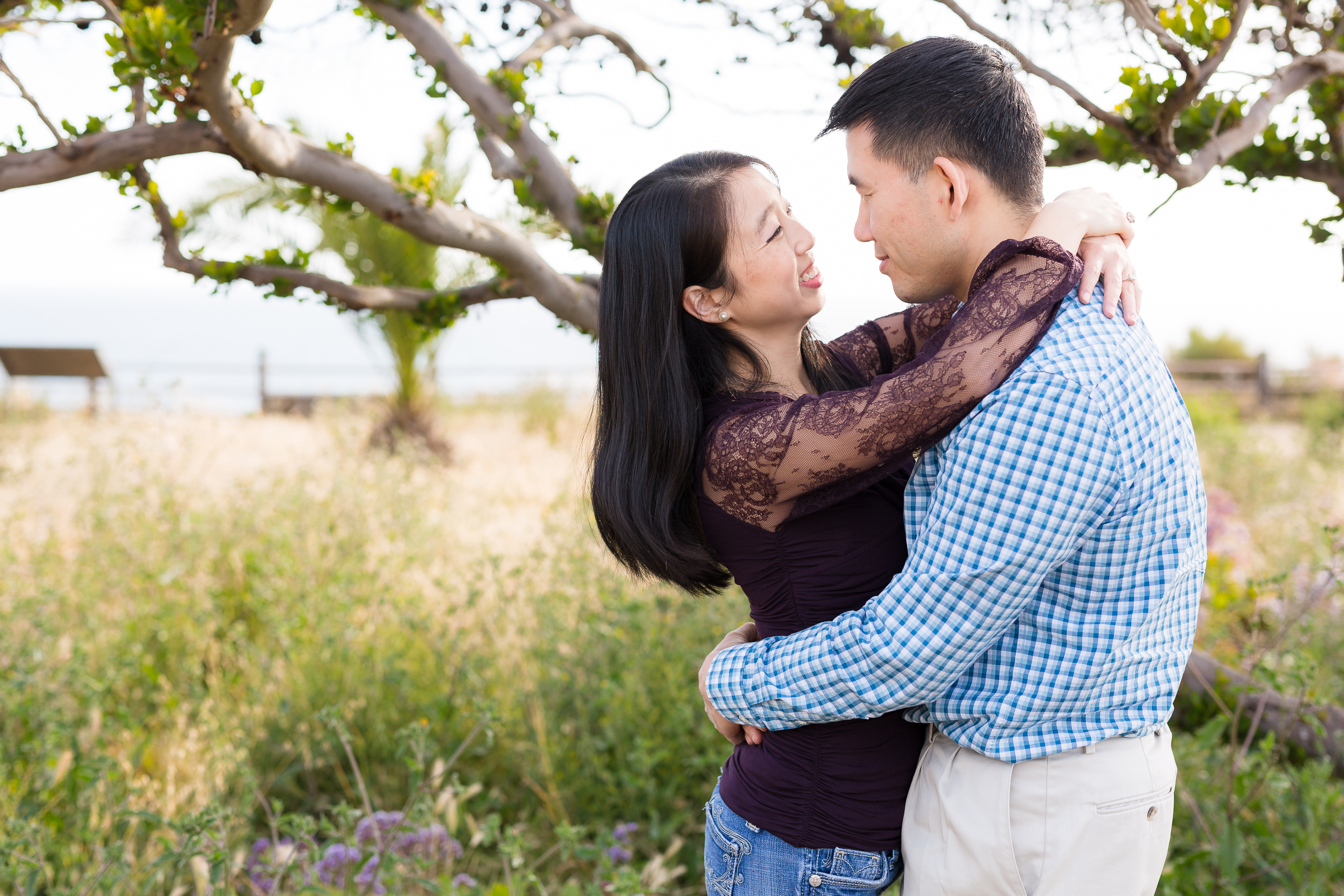 Asian couple dancing by tree on cliffside