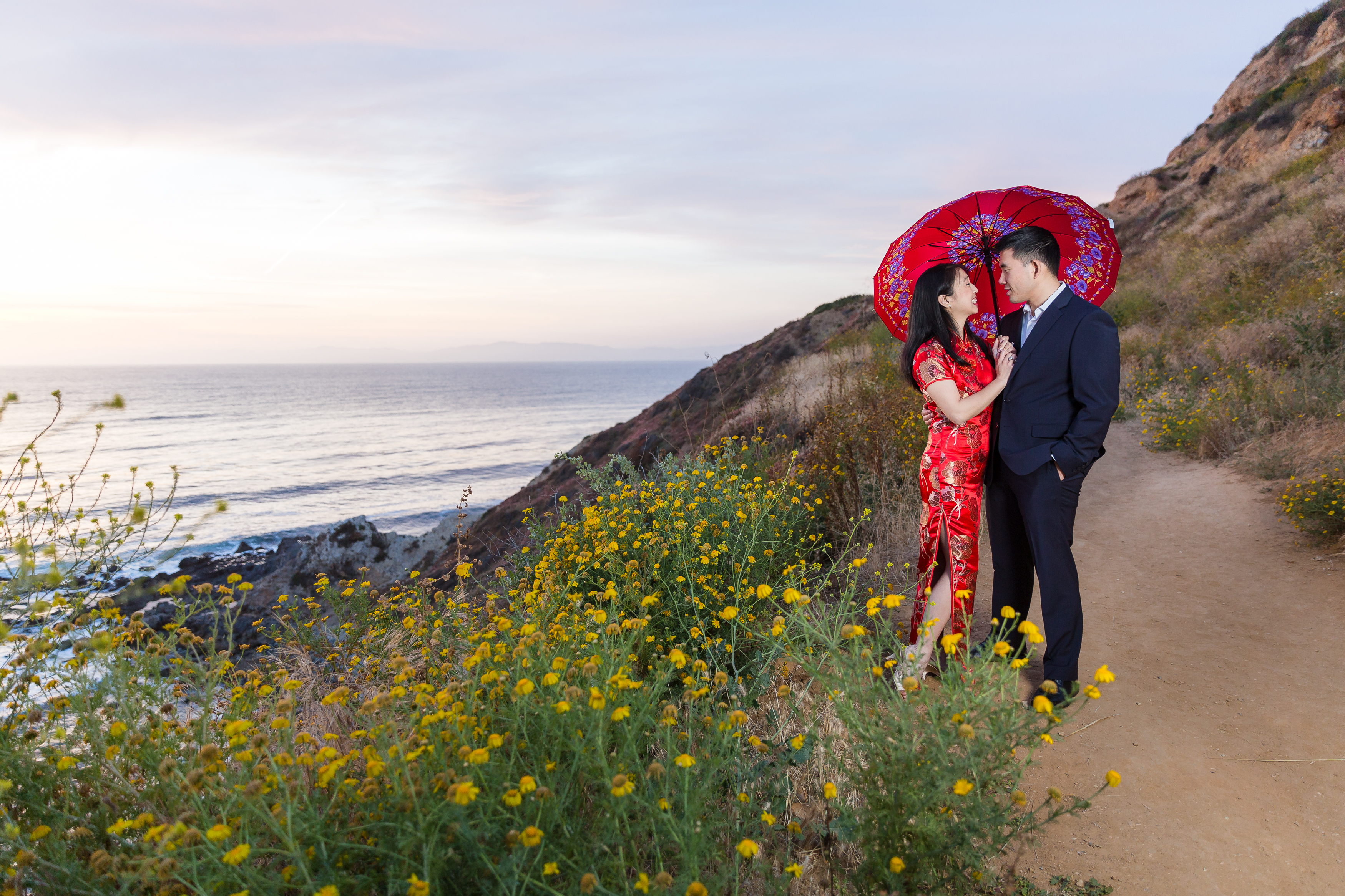 Traditional Asian couple gazing into each other's eyes with red umbrella