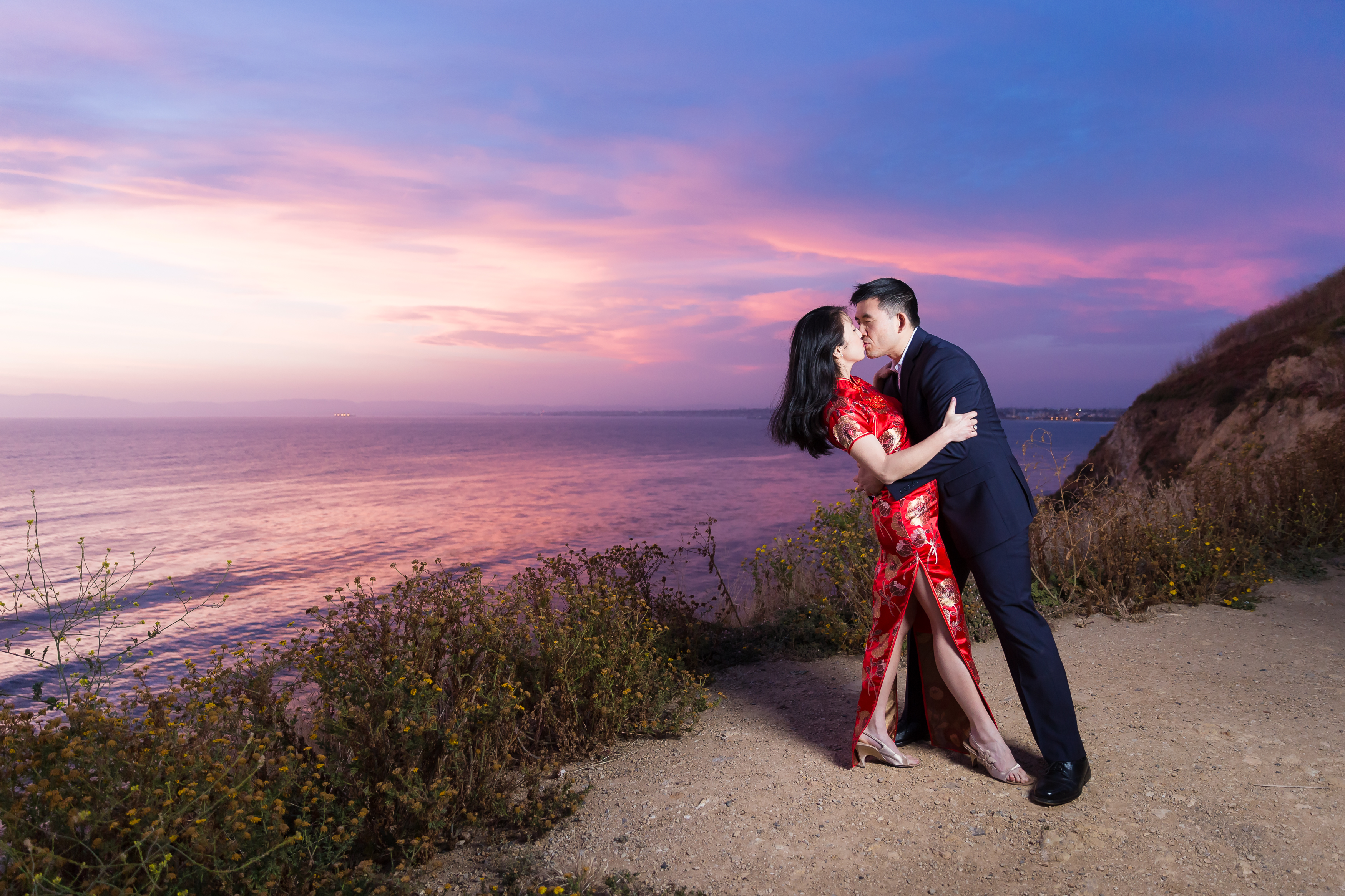 Man dipping woman back into a kiss on cliffside during sunset in Palos Verdes