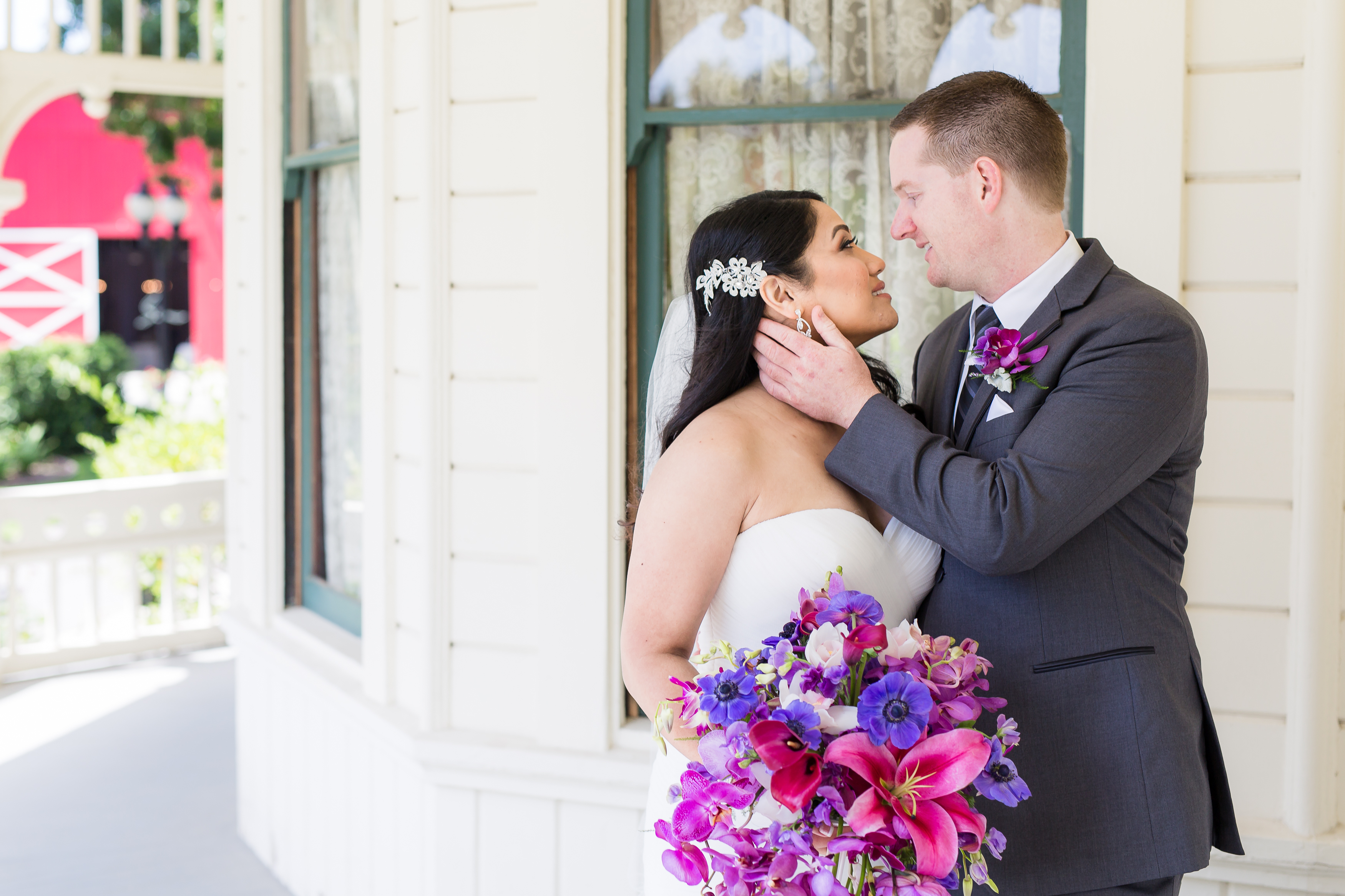 Groom pulling bride in for a kiss by ranch house