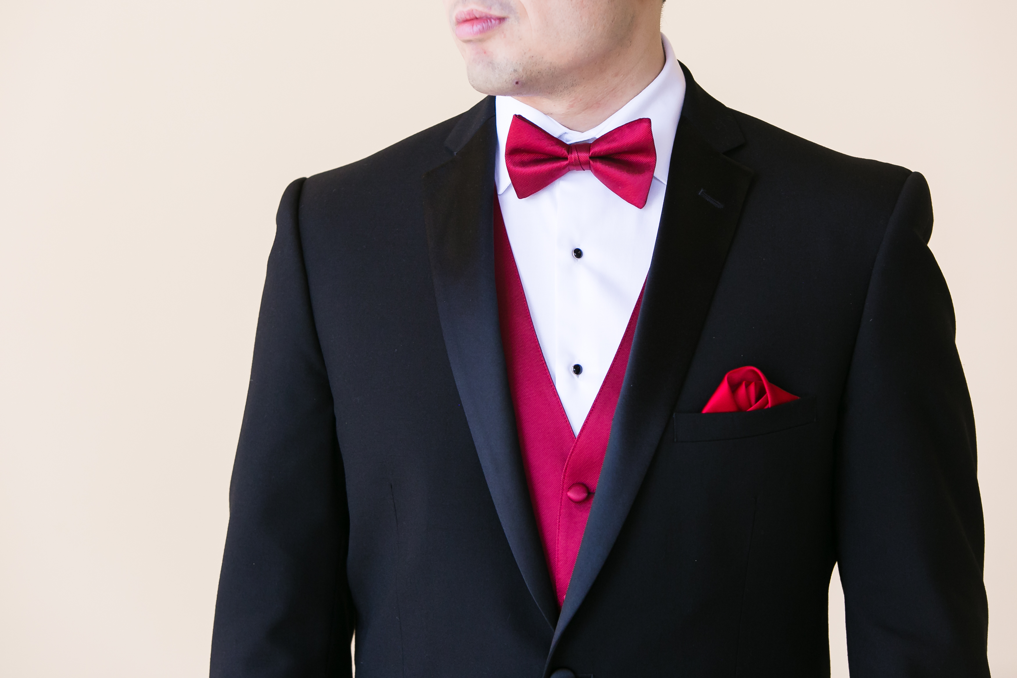 Black tuxedo with a red vest, bow tie and pocket square