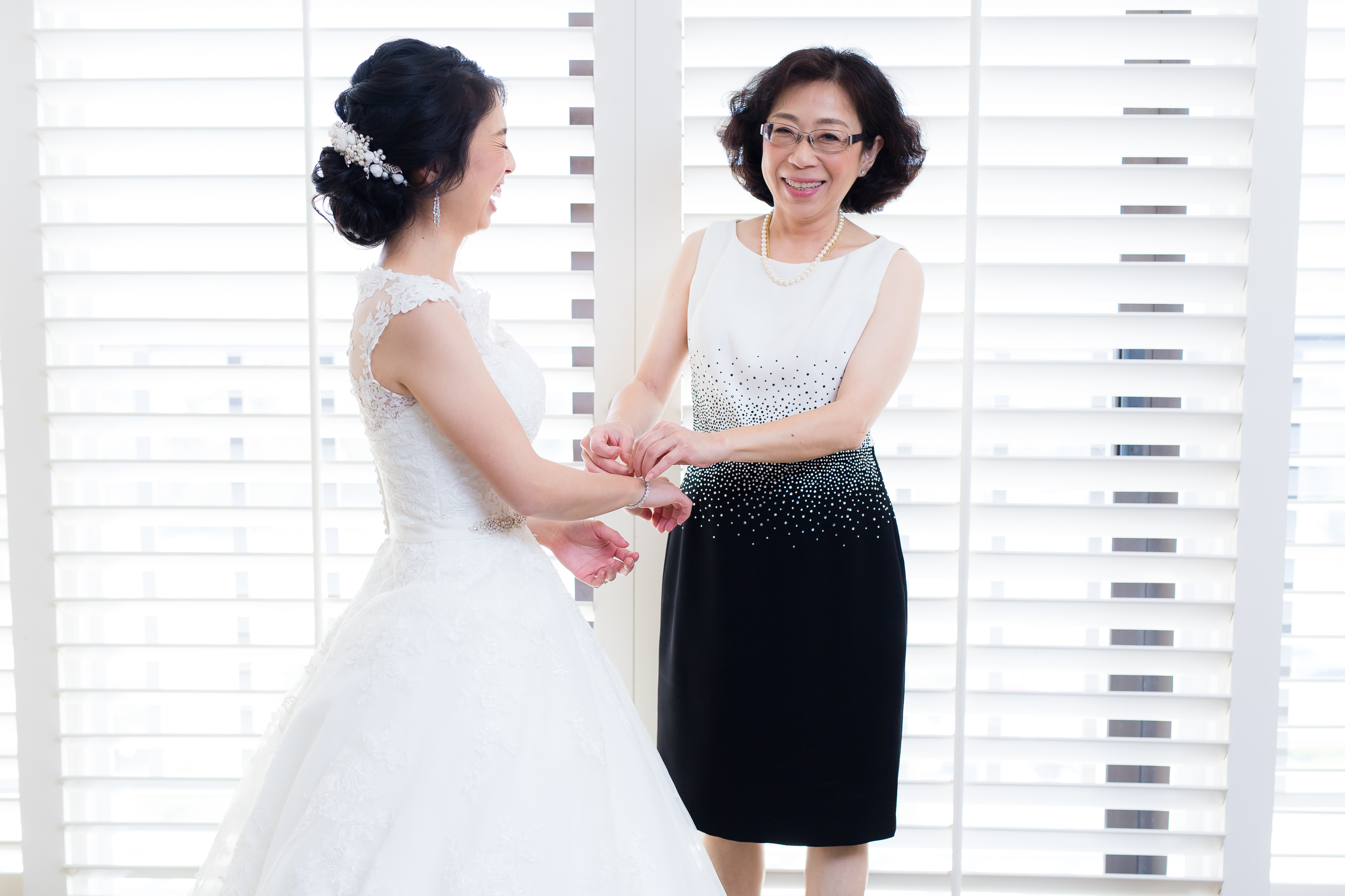 Mom helping bride put on bracelet while laughing