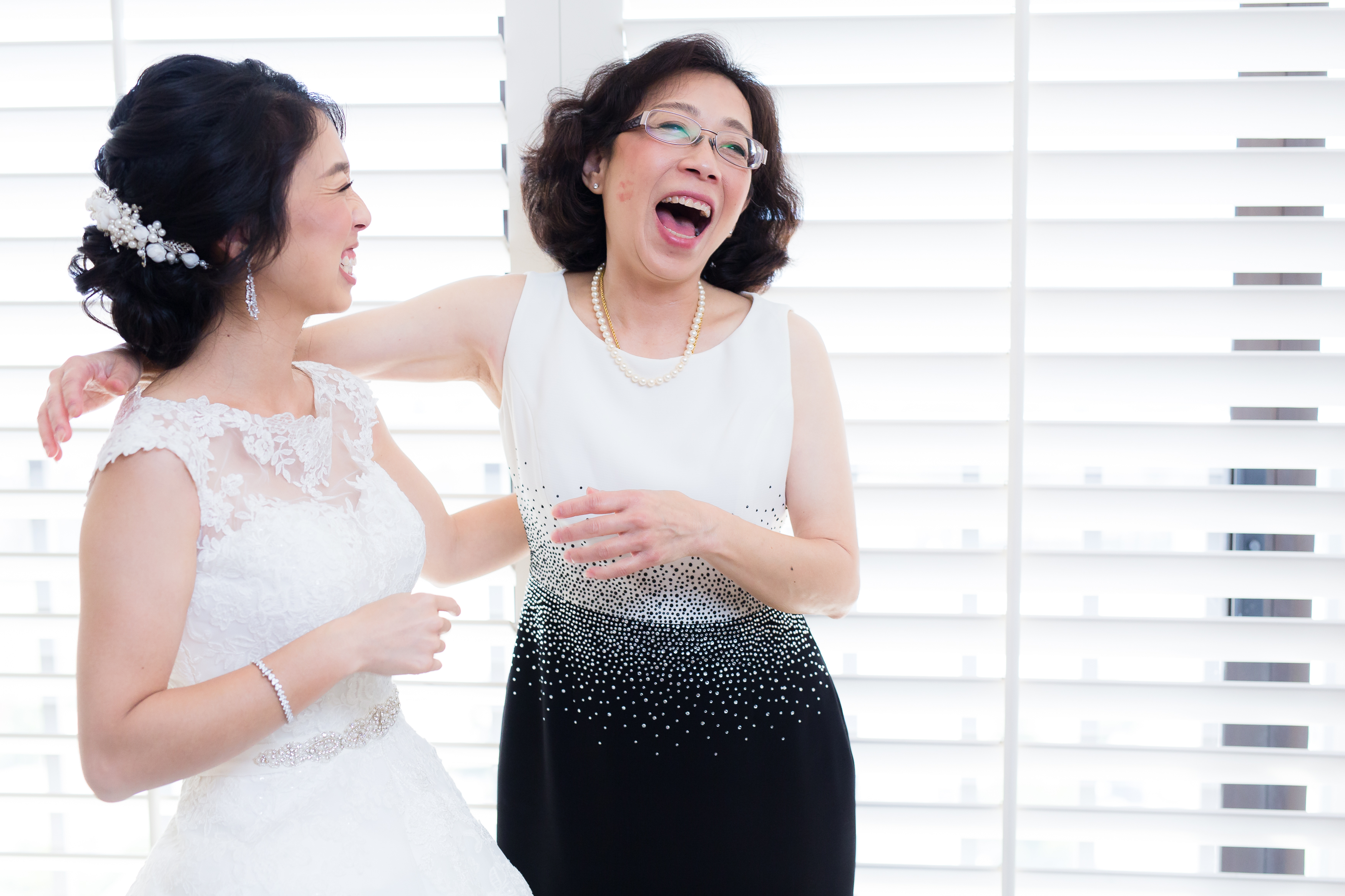 Bride and mom laughing after daughter leaves lipstick kiss mark on face