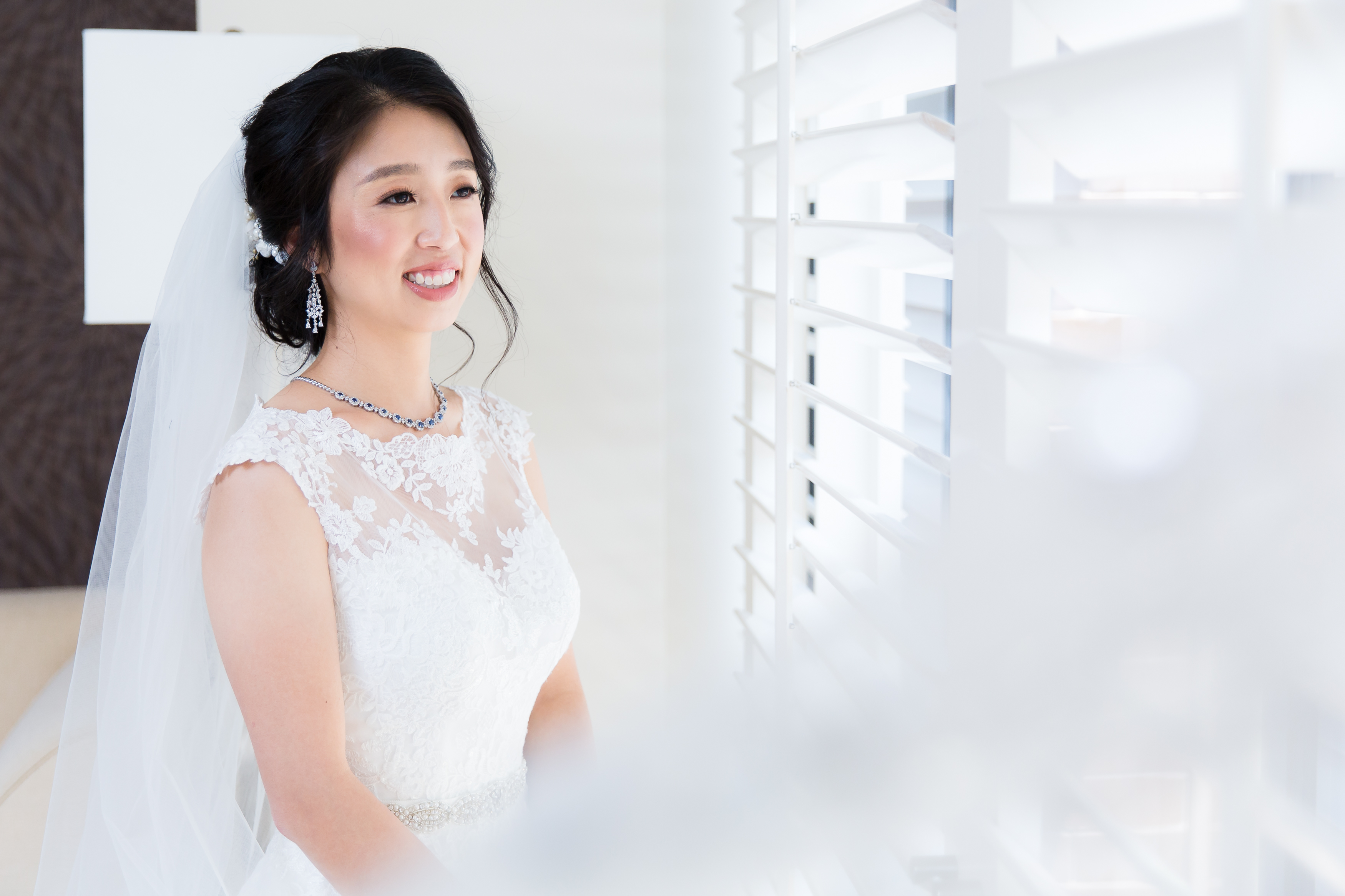 Half body portrait of asian bride behind veil against window Pacific Palms Resort Wedding