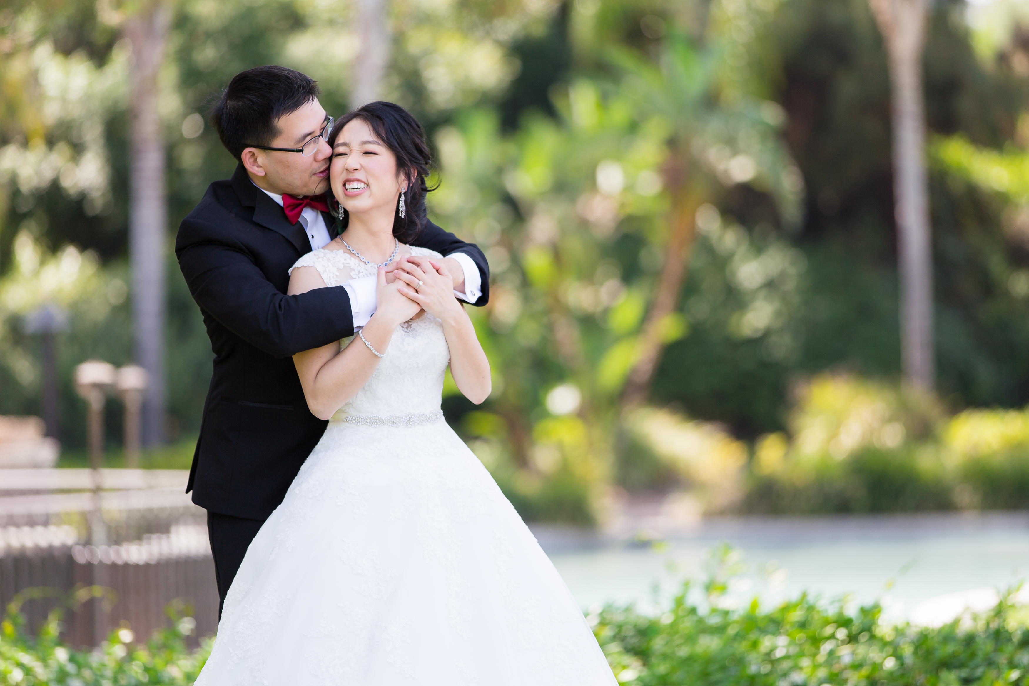 Groom sweetly kissing bride on cheek at Pacific Palms Resort