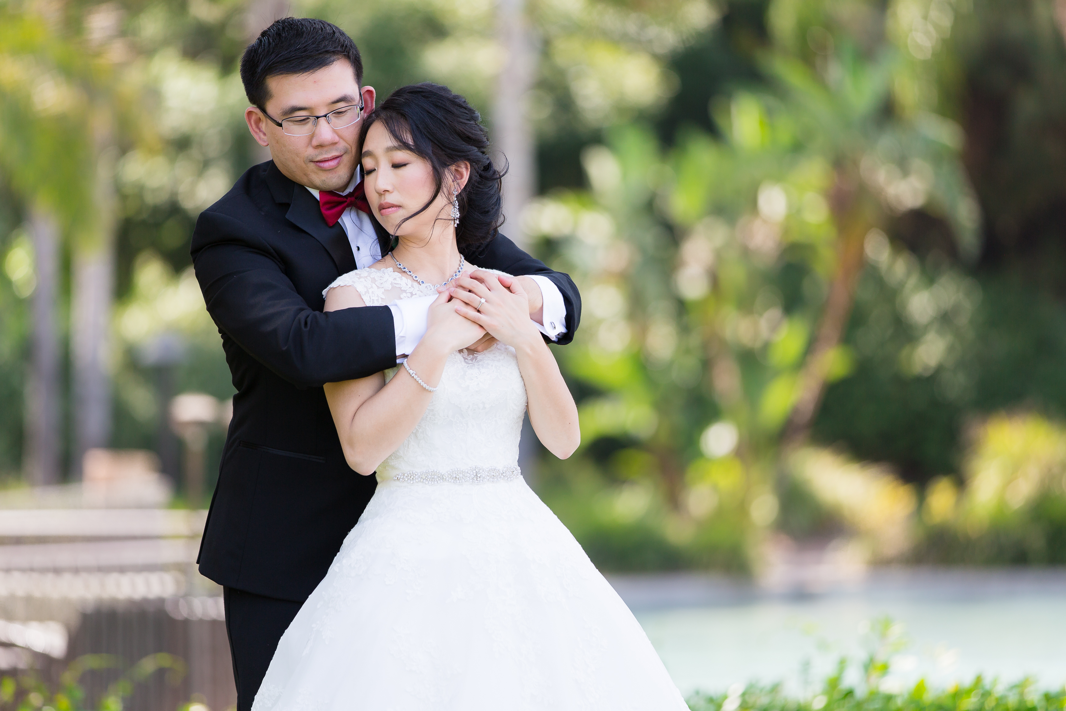 Groom hugging bride from behind romantically