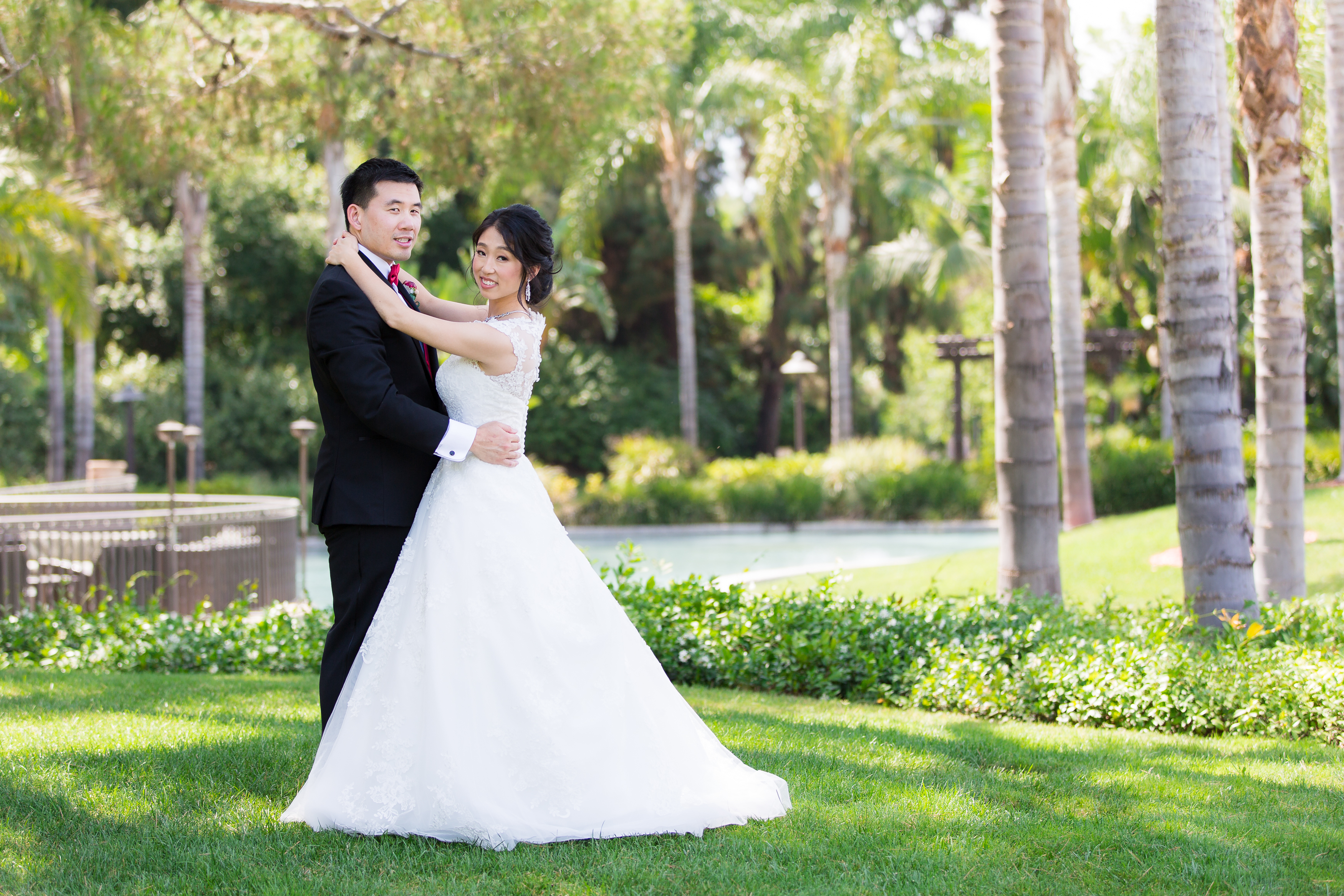 Bride and groom hugging in grass surrounded by palm trees