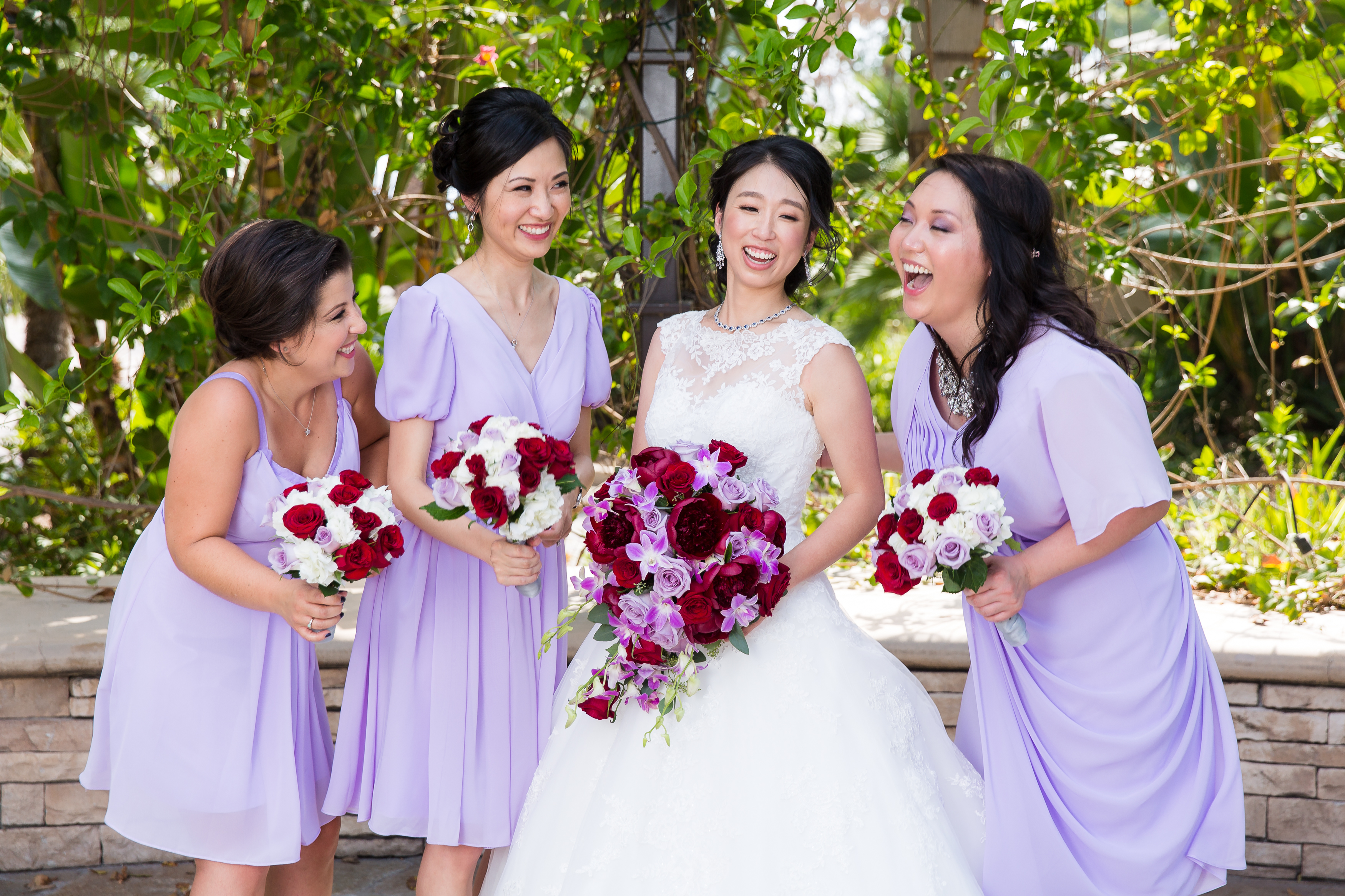 Wedding party laughing in purple dresses next to trees