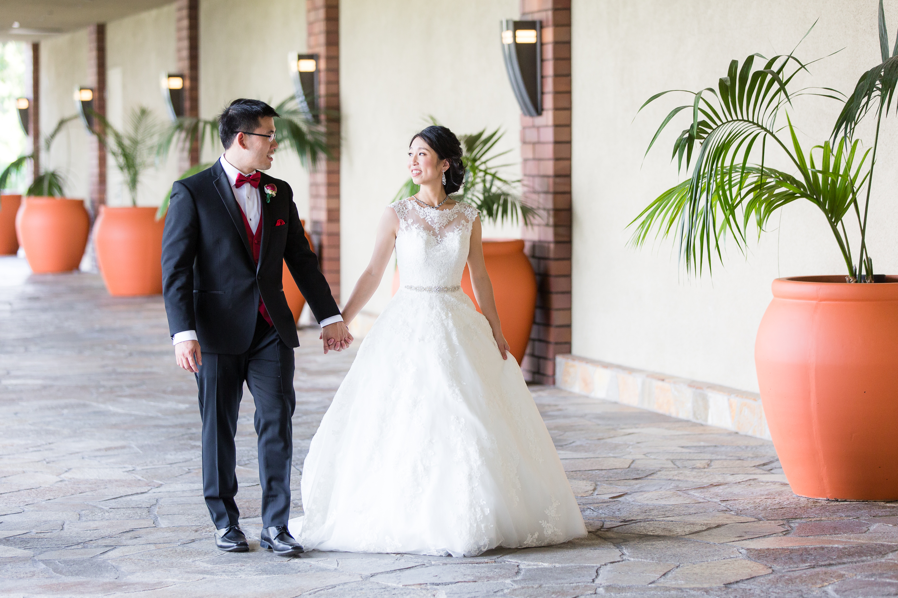Bride and groom holding hands and walking down a hallway