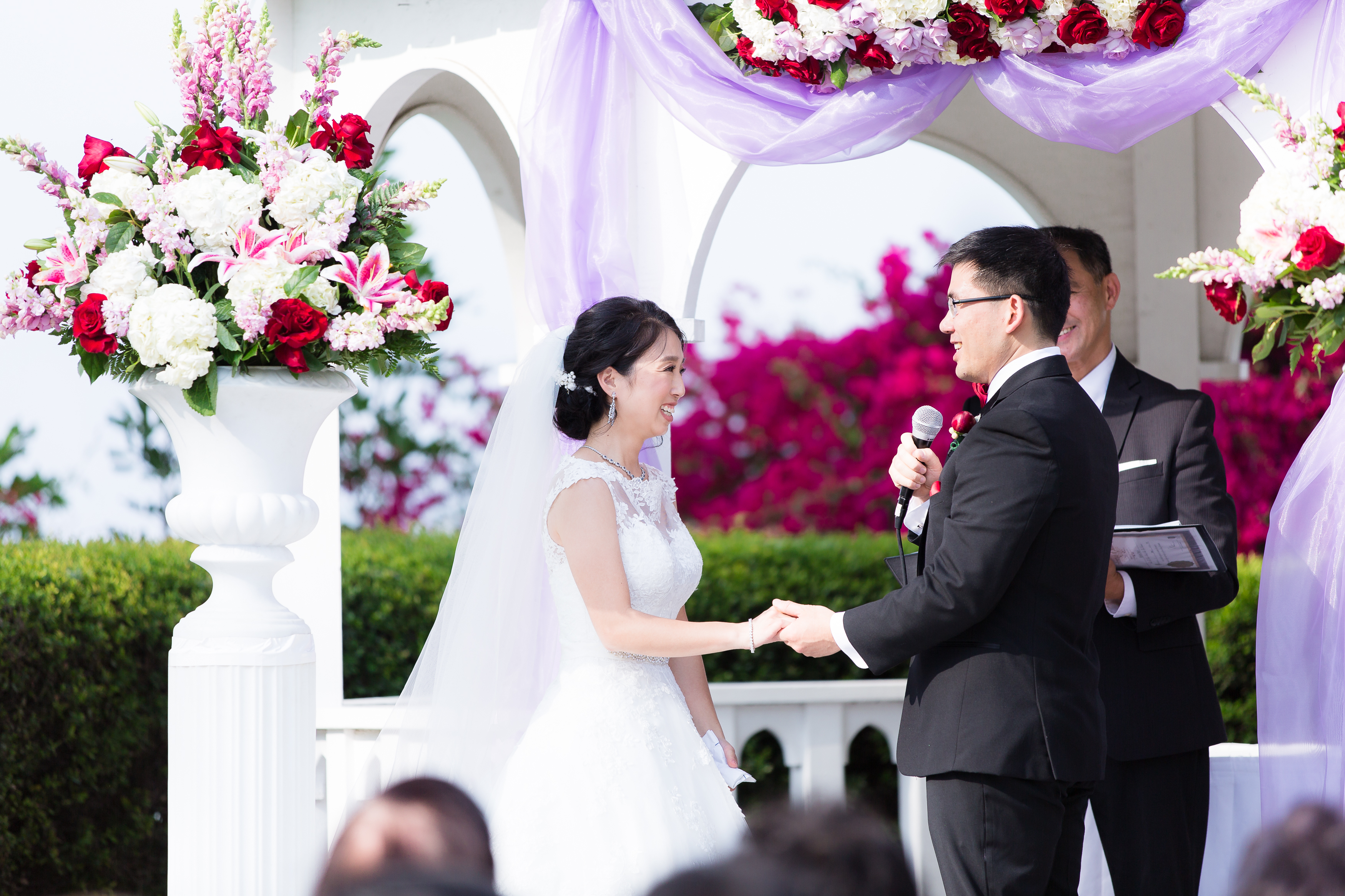 Wedding couple laughing while exchanging vows and holding hands