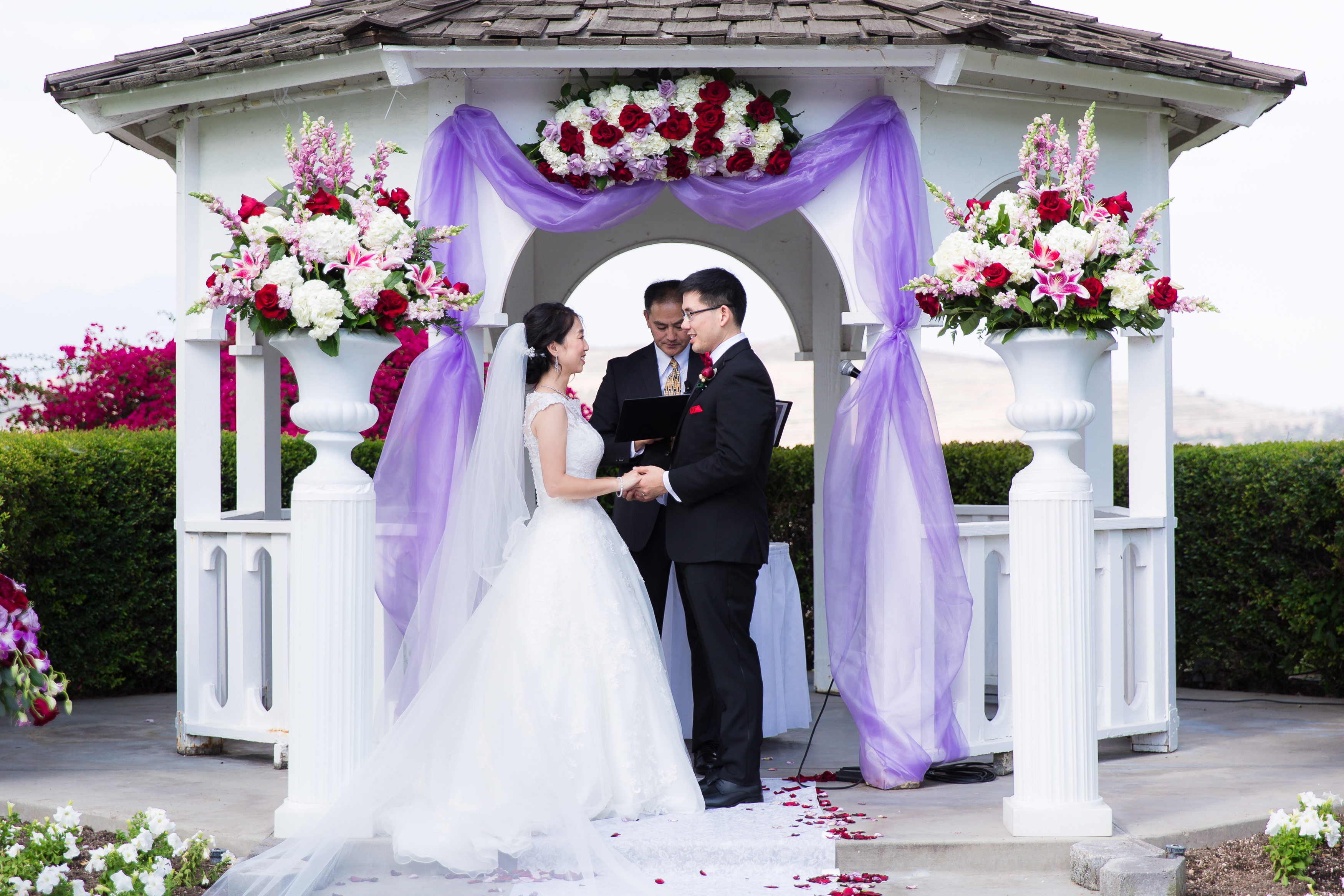 Wedding couple holding hands under gazebo during wedding ceremony