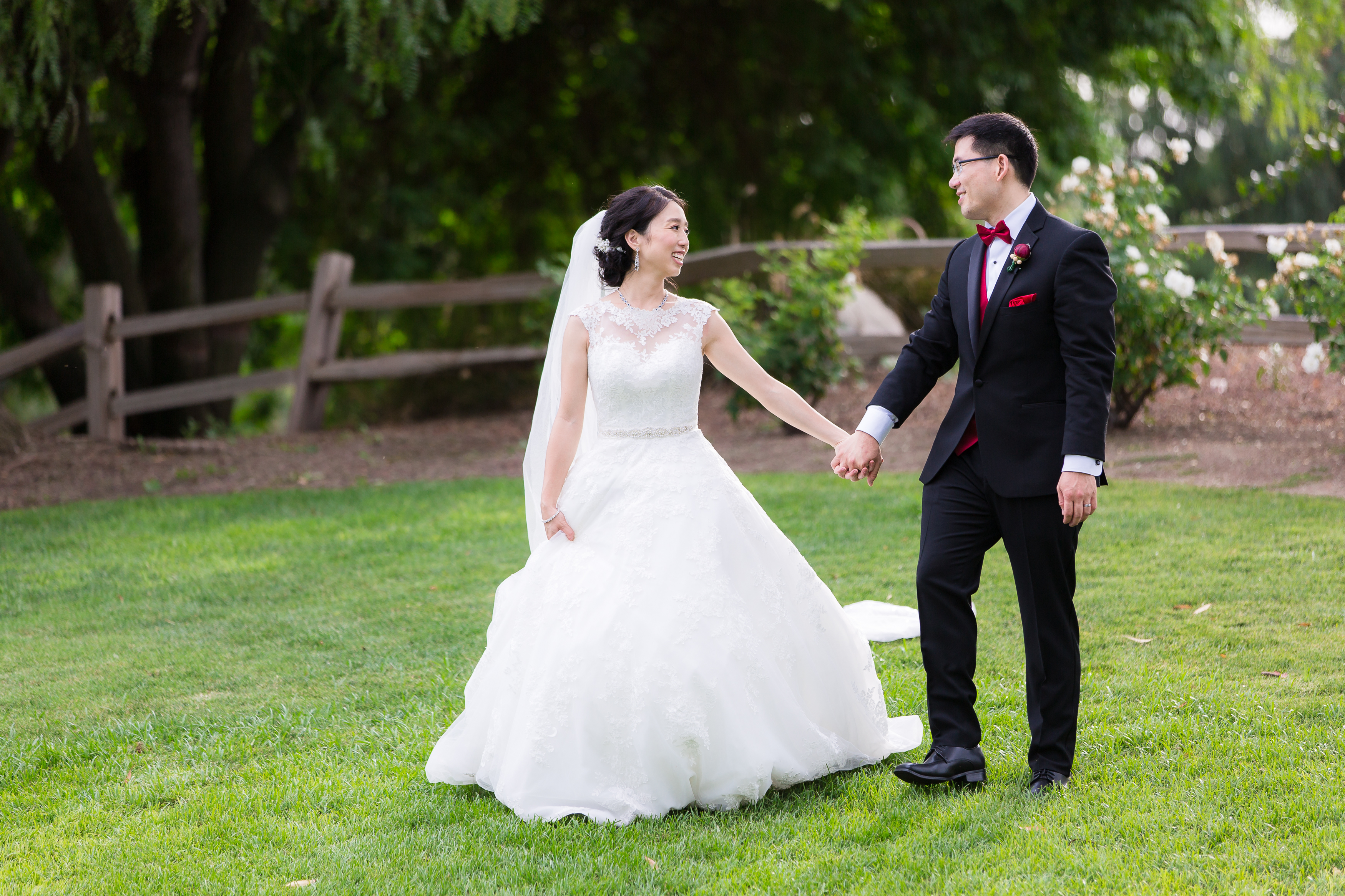 Bride holding groom's hand walking side by side and smiling at each other