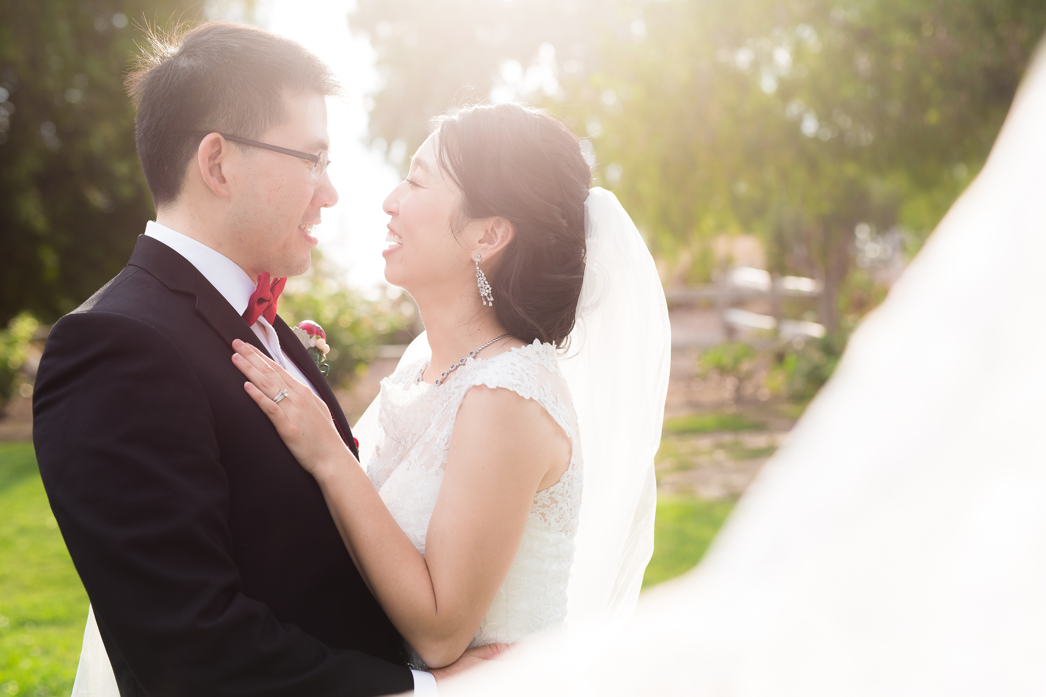 Wedding couple laughing at each other behind floating veil