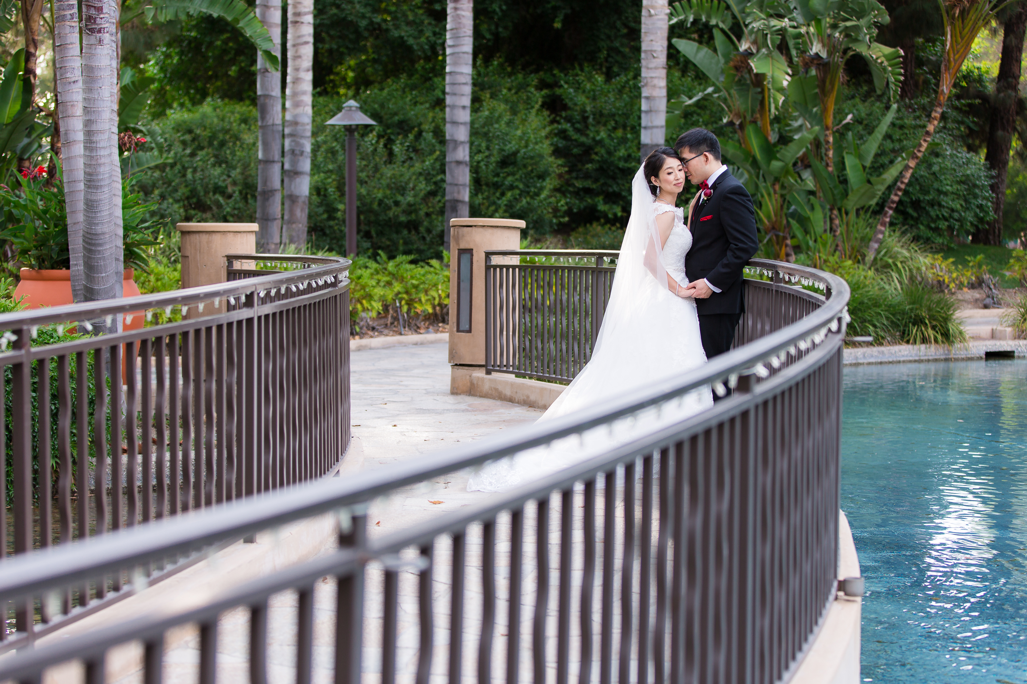 Wedding couple holding hands on bridge at Pacific Palms Resort Wedding
