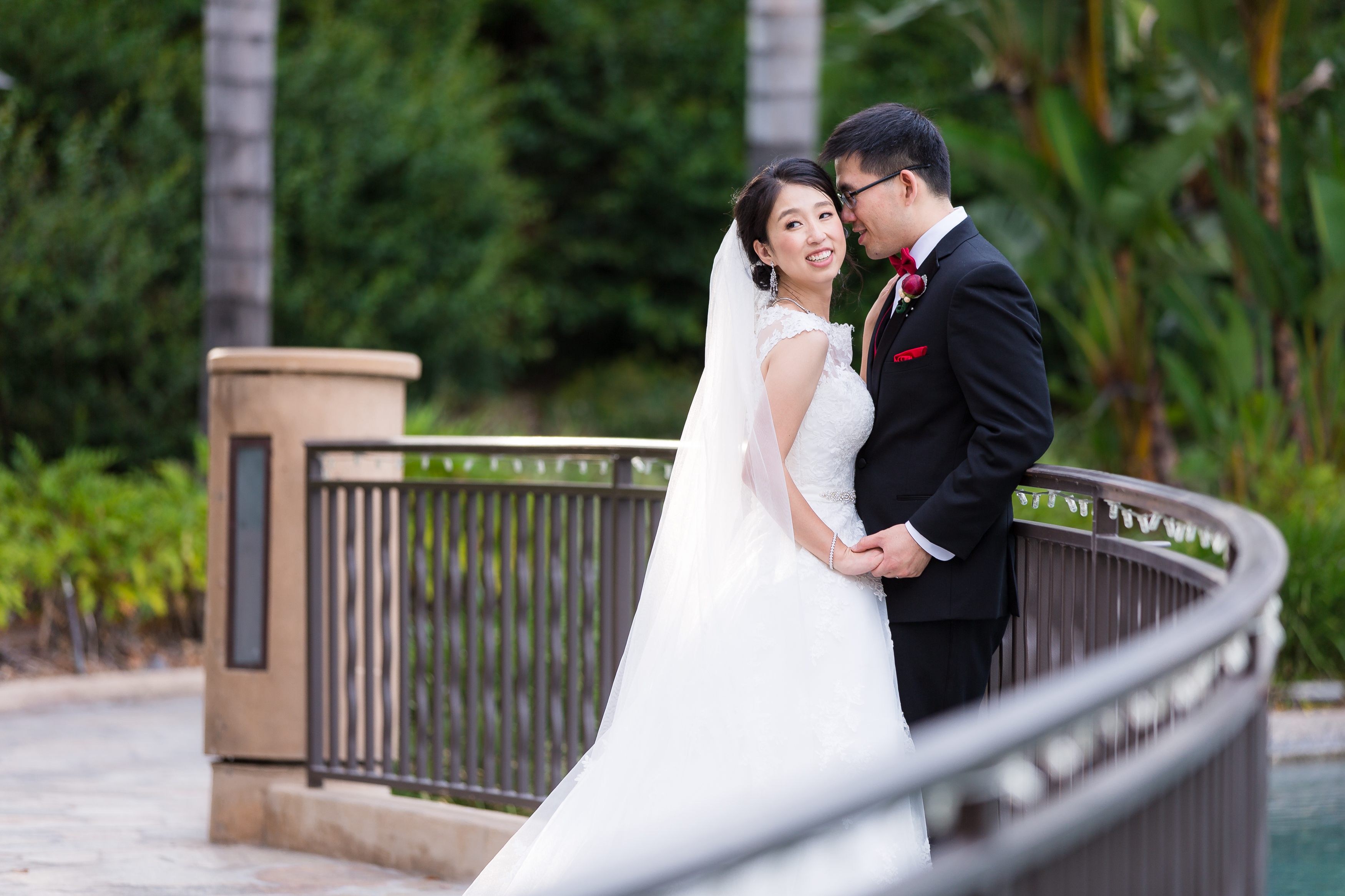 Sweet couple whispering against bridge at resort wedding in California