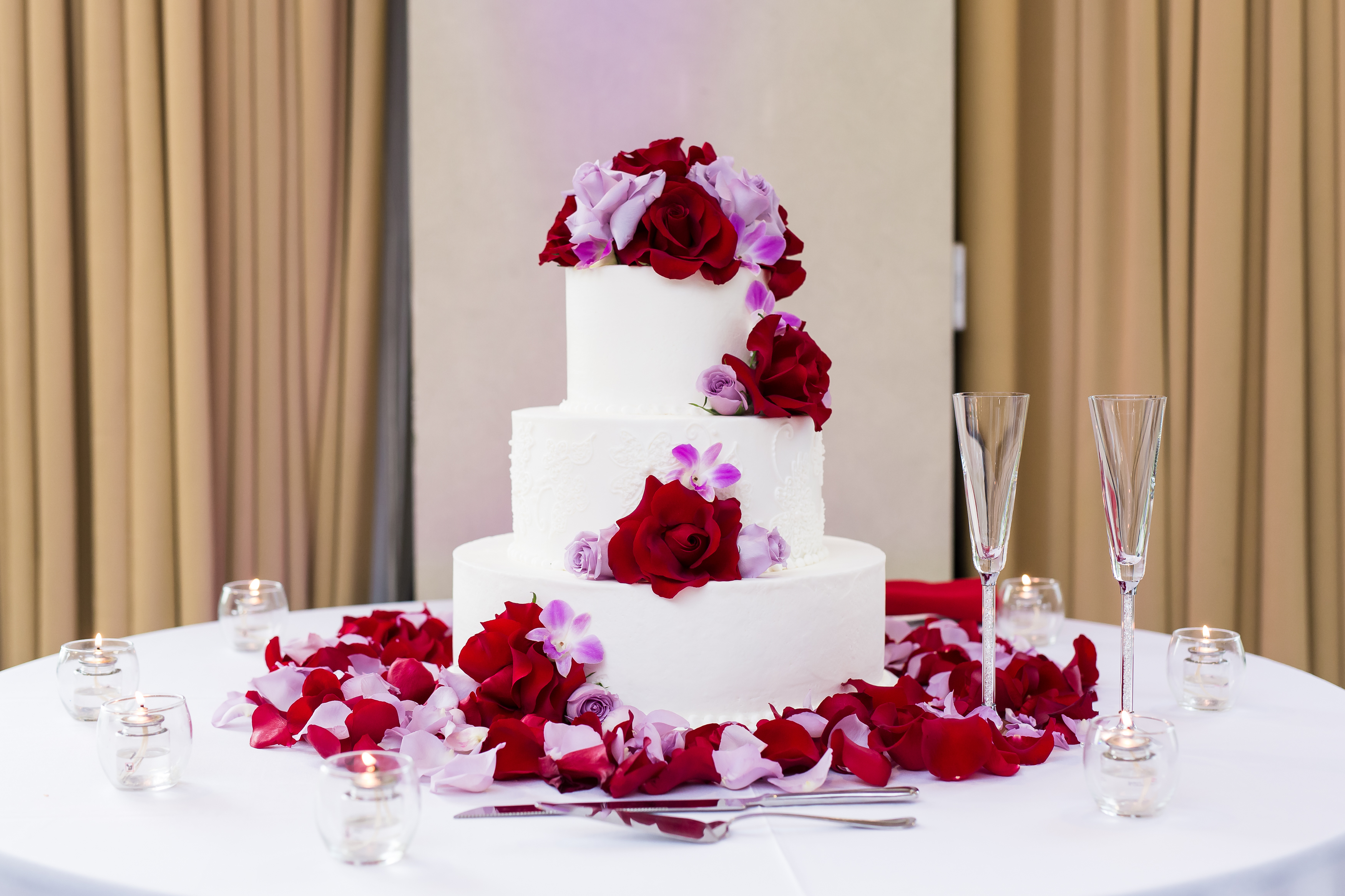 White tiered wedding cake with red and purple flowers at Pacific Palms Resort Wedding