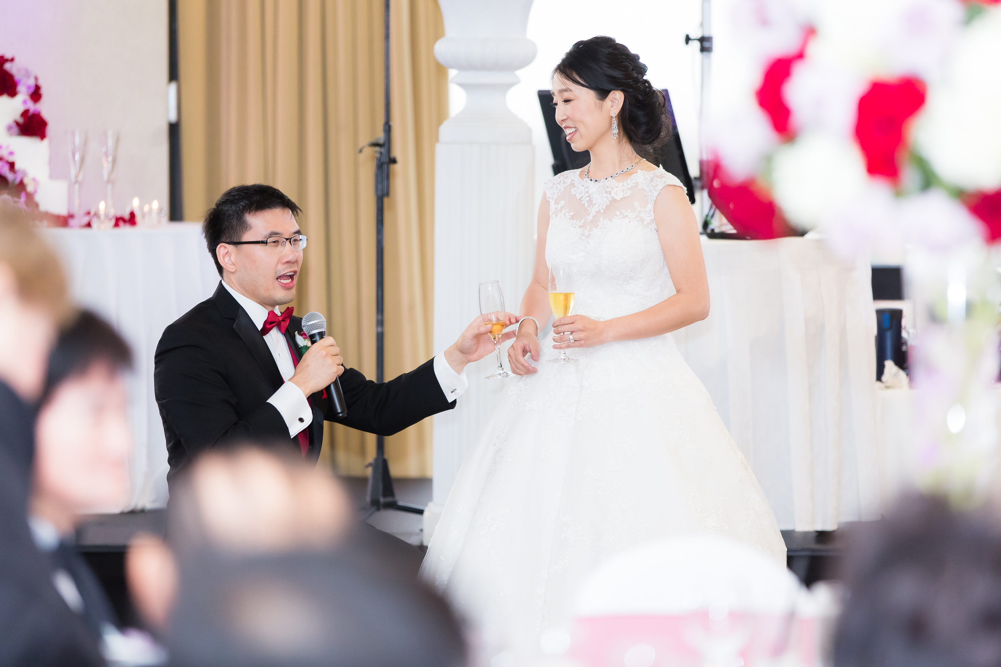 Groom kneels by bride and tells guests story of their proposal