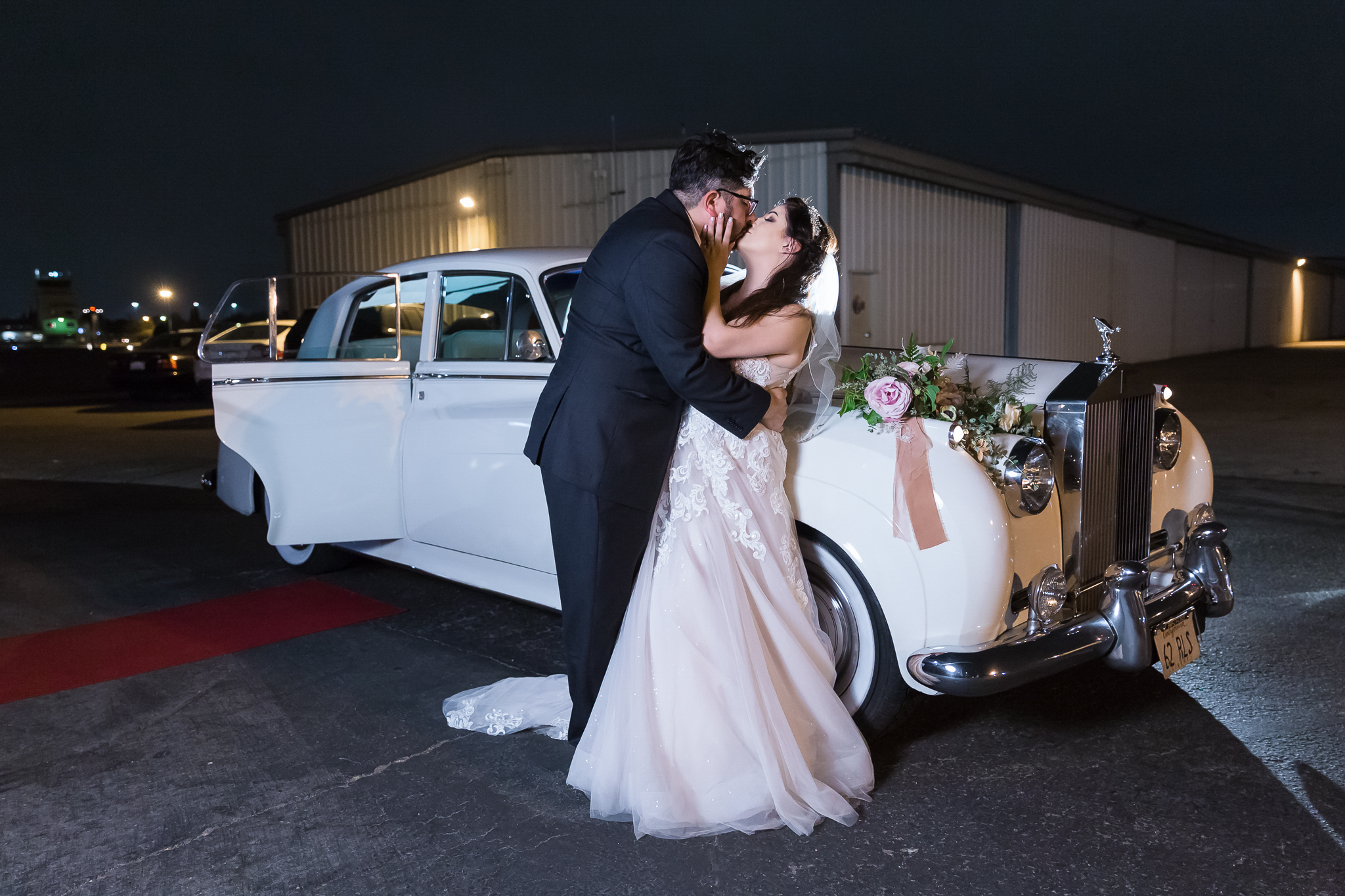 Bride groom kissing in front of vintage roll royce
