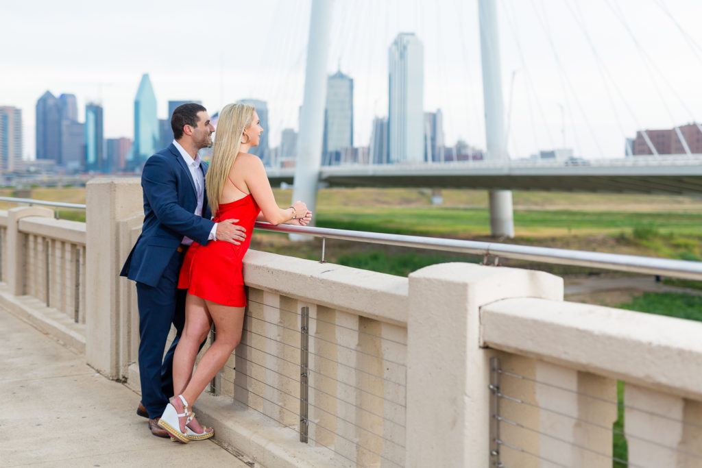 woman in red dress and man in blue suit admiring dallas skyline